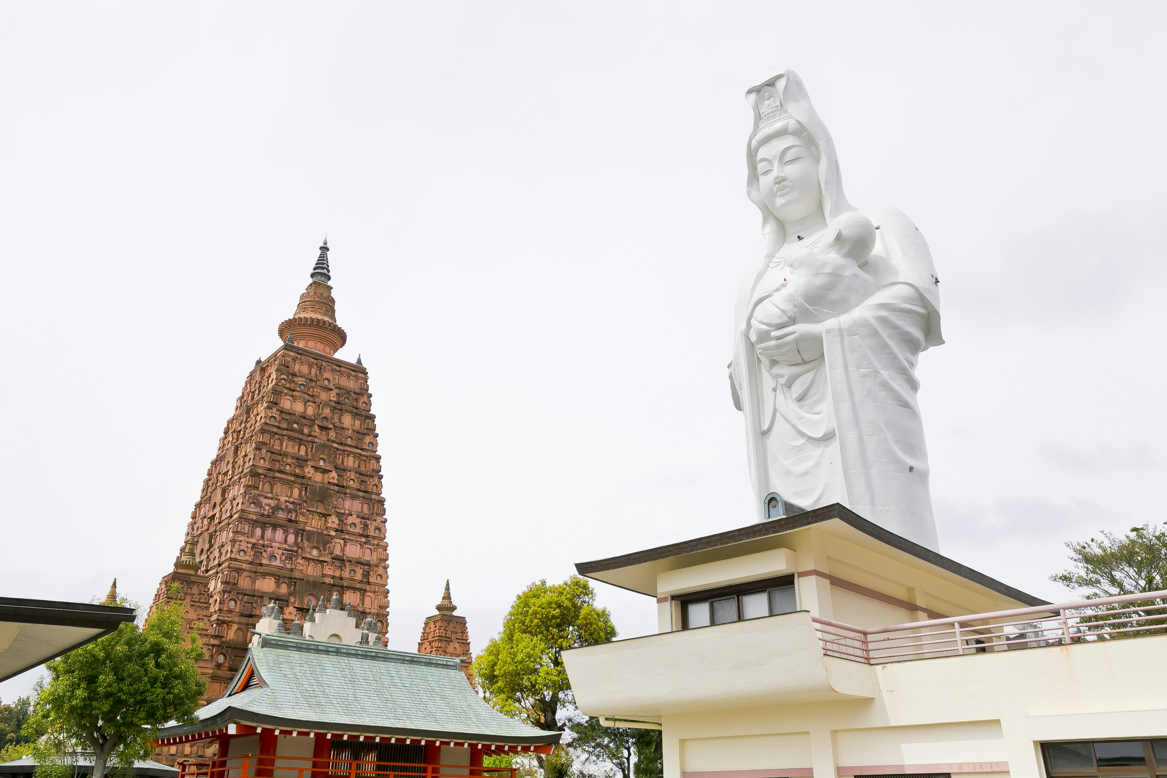 Grande statua di Kuan Yin accanto a un antico tempio