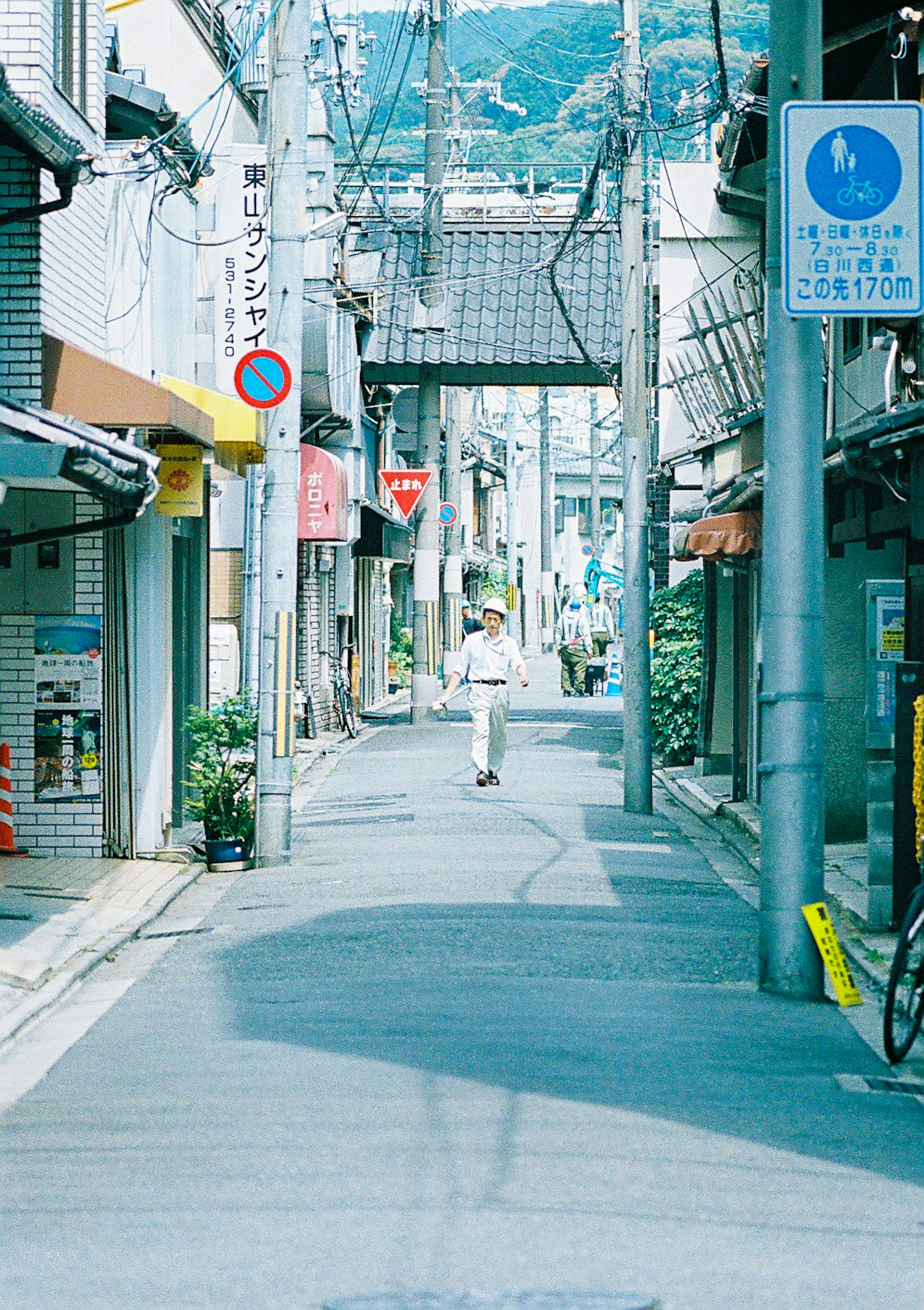 Eine Person geht eine ruhige japanische Nebenstraße entlang