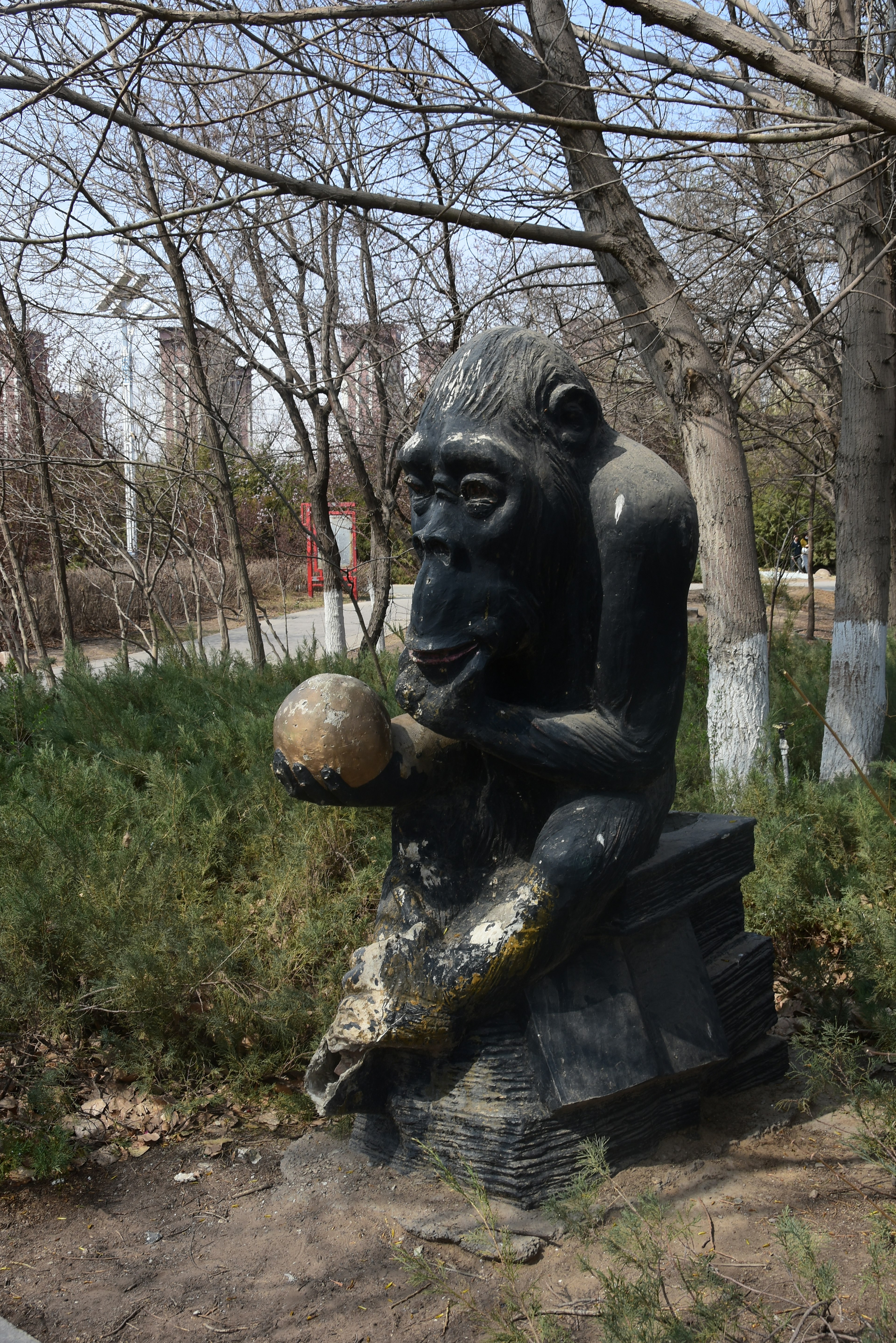 Scultura di scimmia nera che tiene una palla in un parco