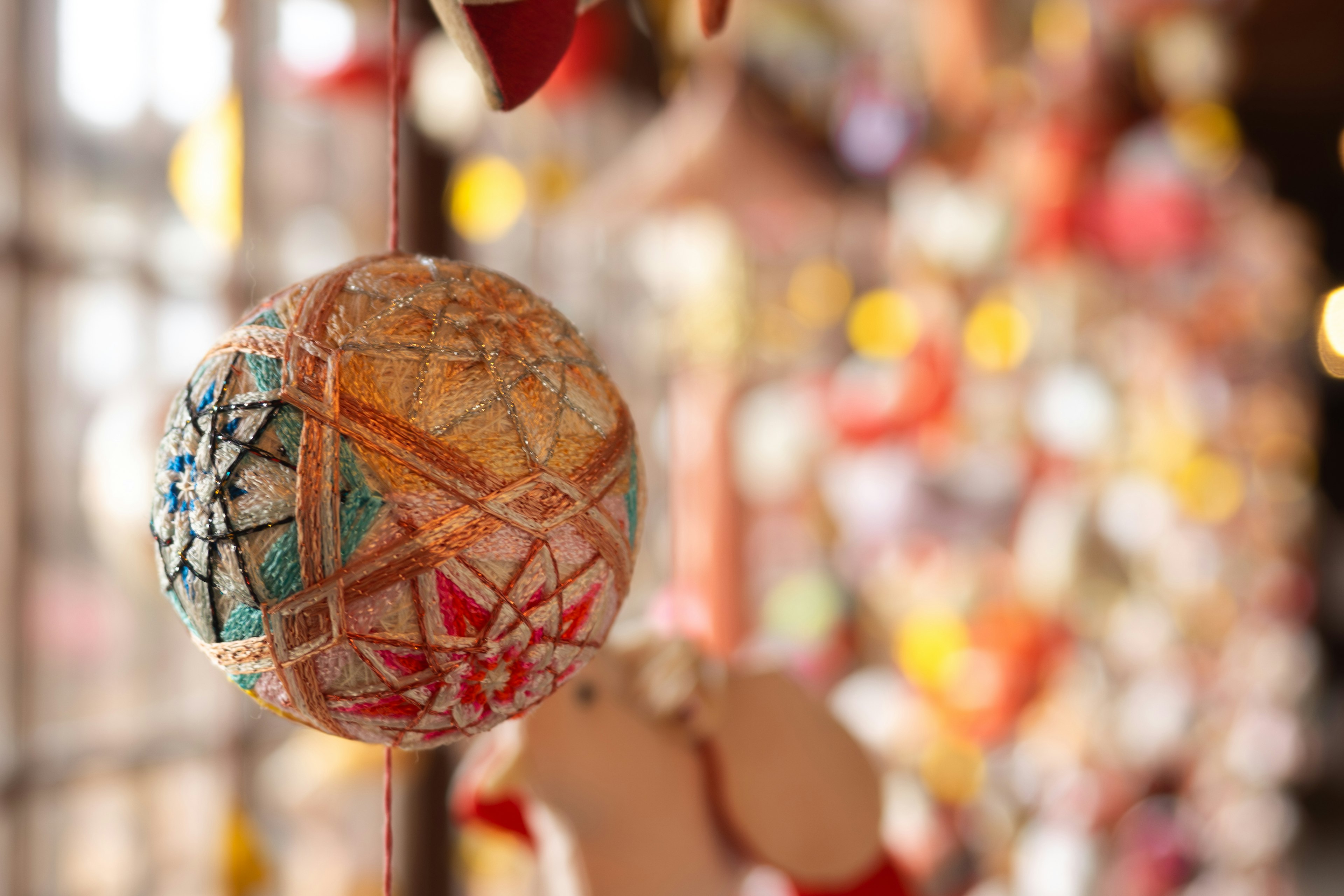 Nahaufnahme einer bunten dekorativen Kugel, die hängt, mit verschwommenen Ornamenten im Hintergrund