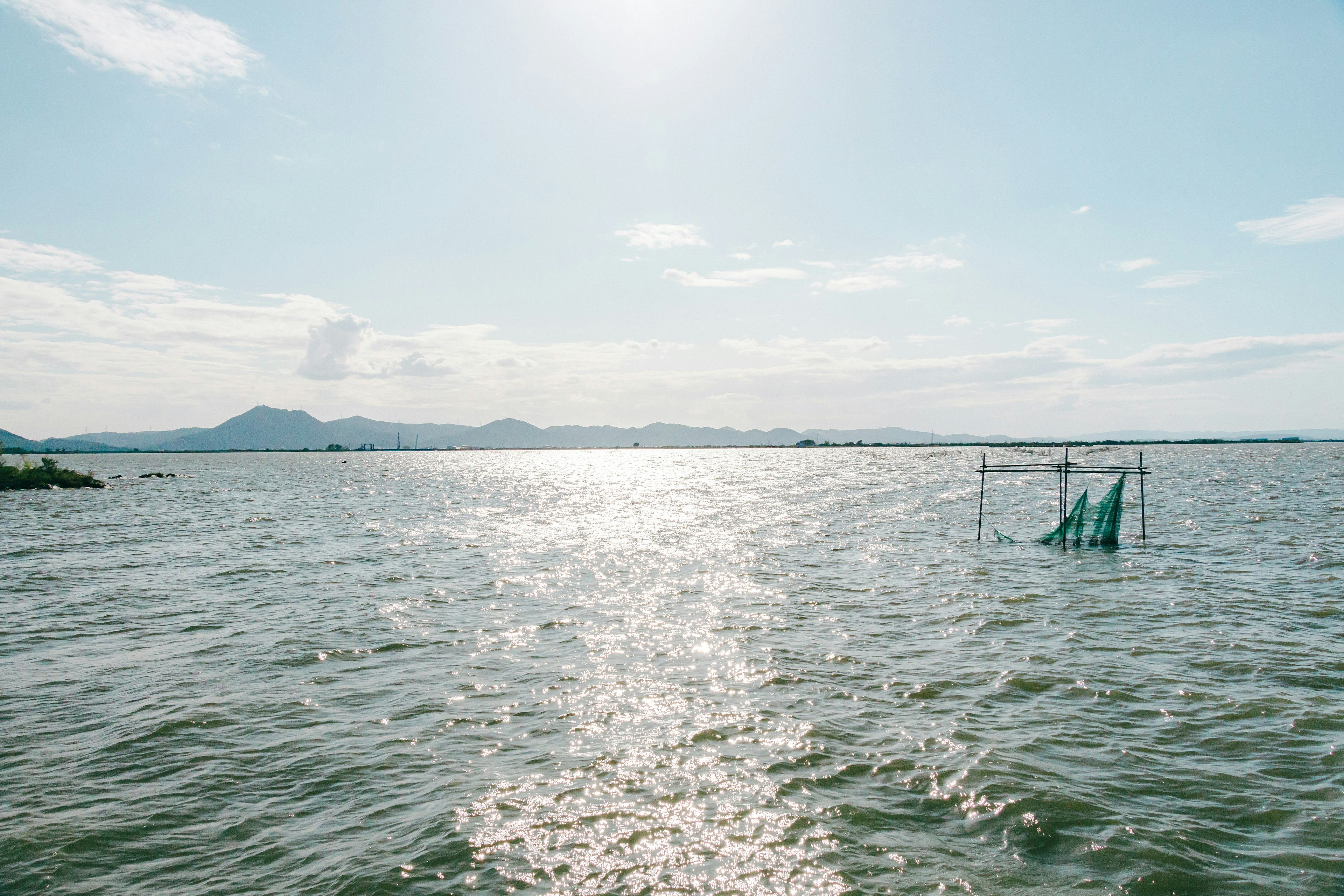 Ruhige Wasseroberfläche, die Sonnenlicht und blauen Himmel reflektiert