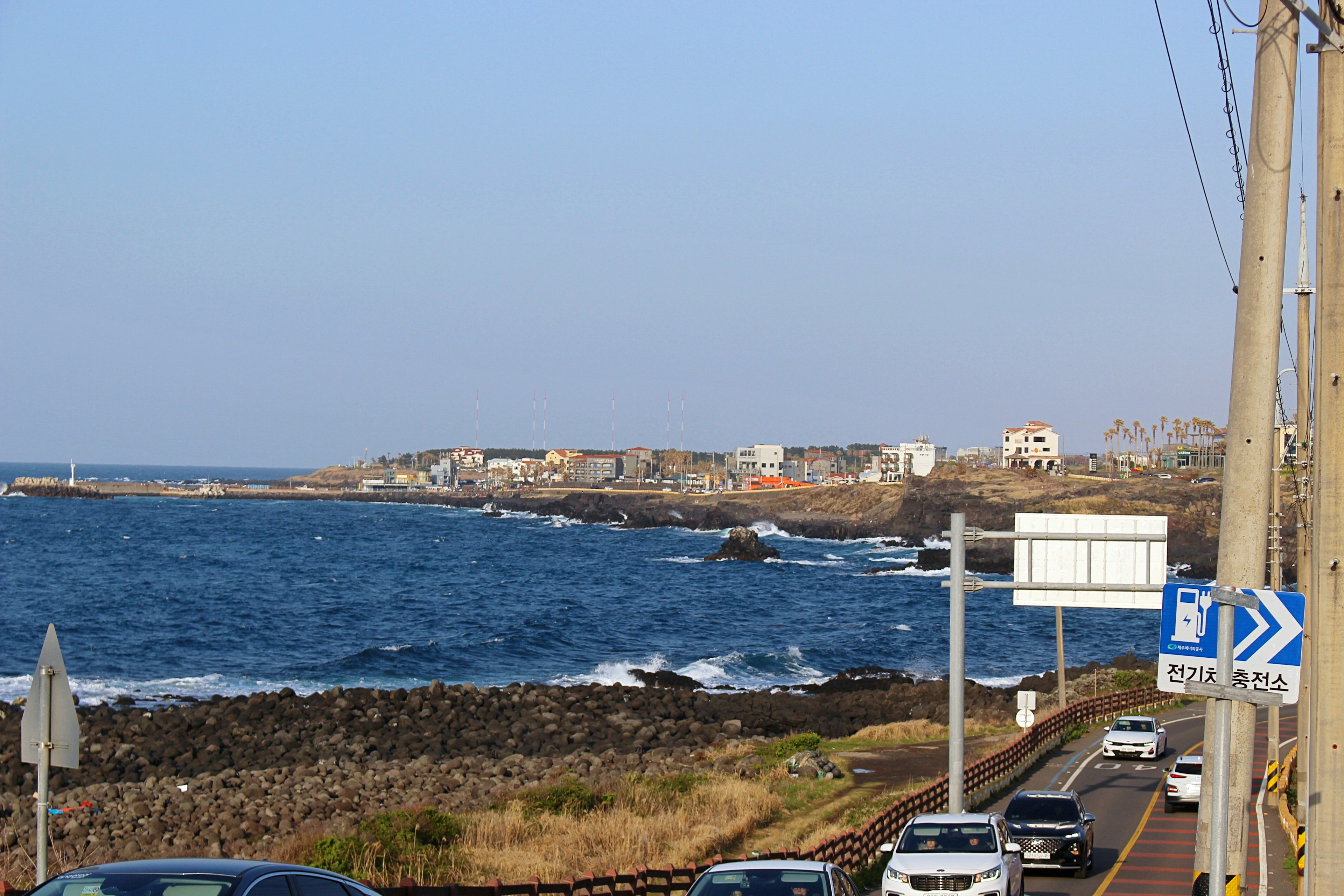 Vista de carretera costera con océano azul casas y rocas dispersas