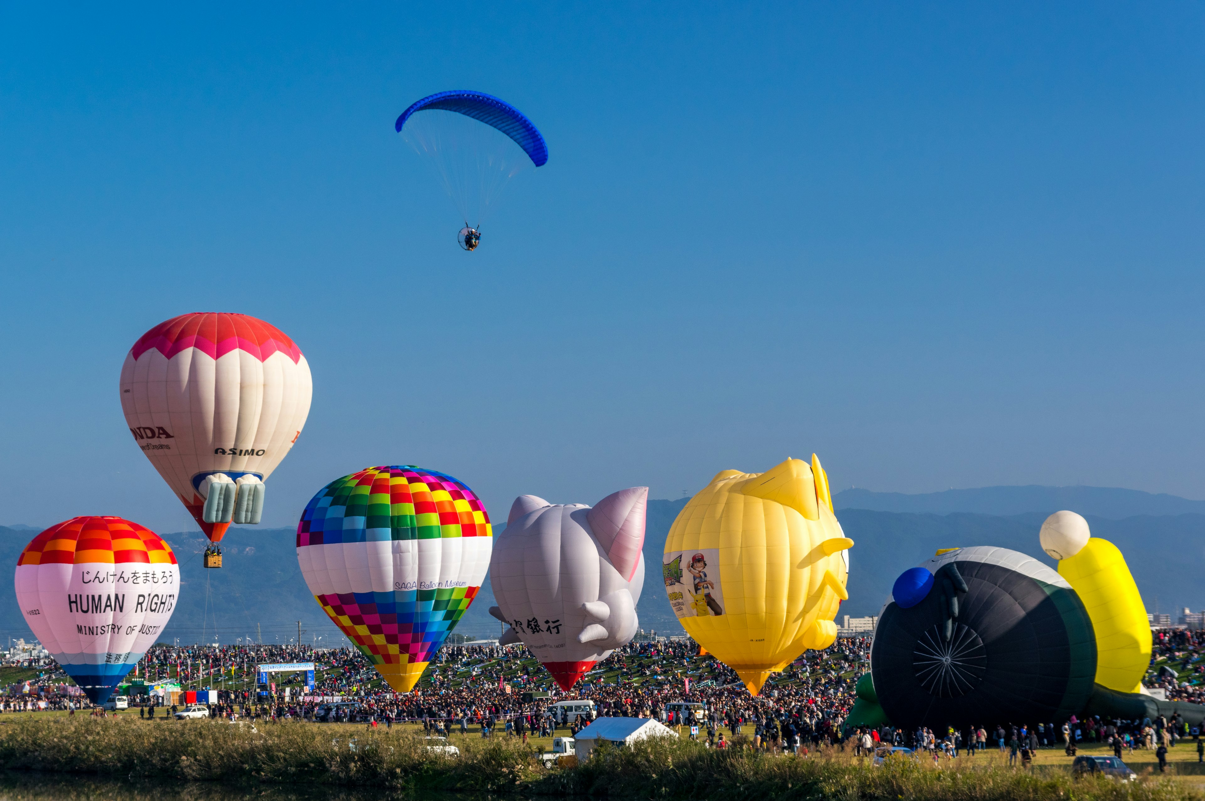 Colorati palloni aerostatici che fluttuano nel cielo con un parapendio