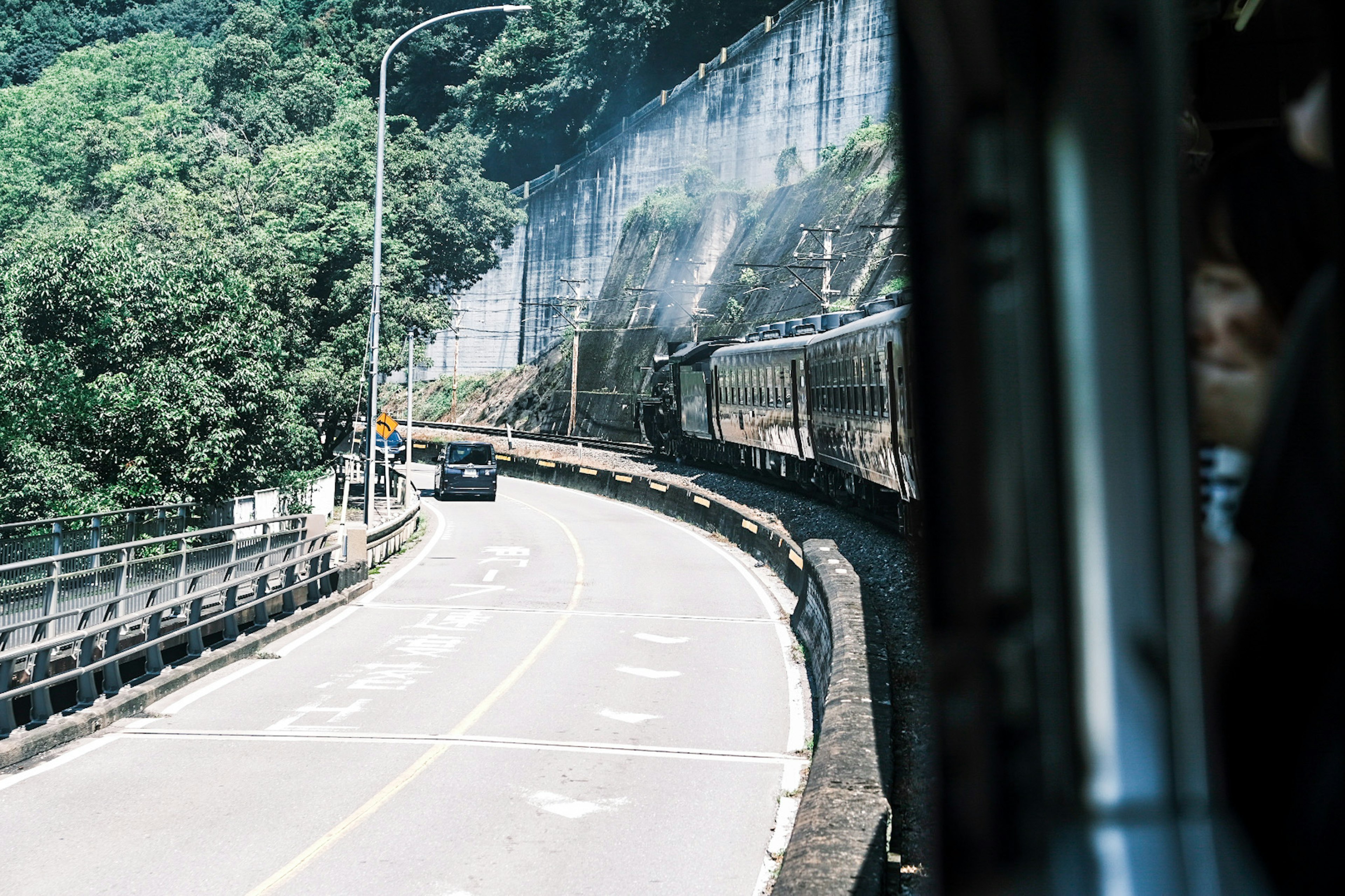 View of a winding road with a car and a train