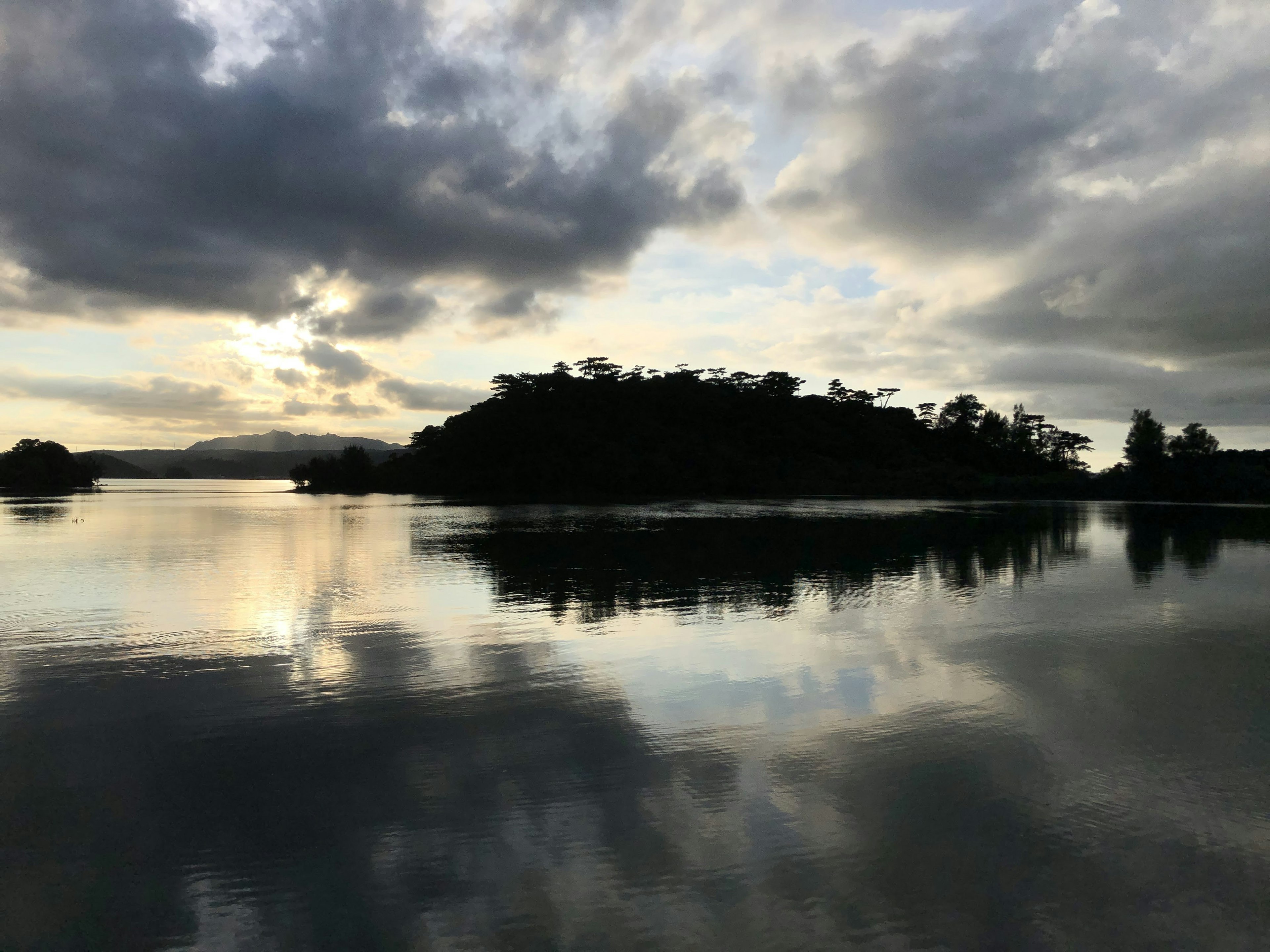 Ruhige Seeszene mit Sonnenuntergang, der sich in einer Insel spiegelt