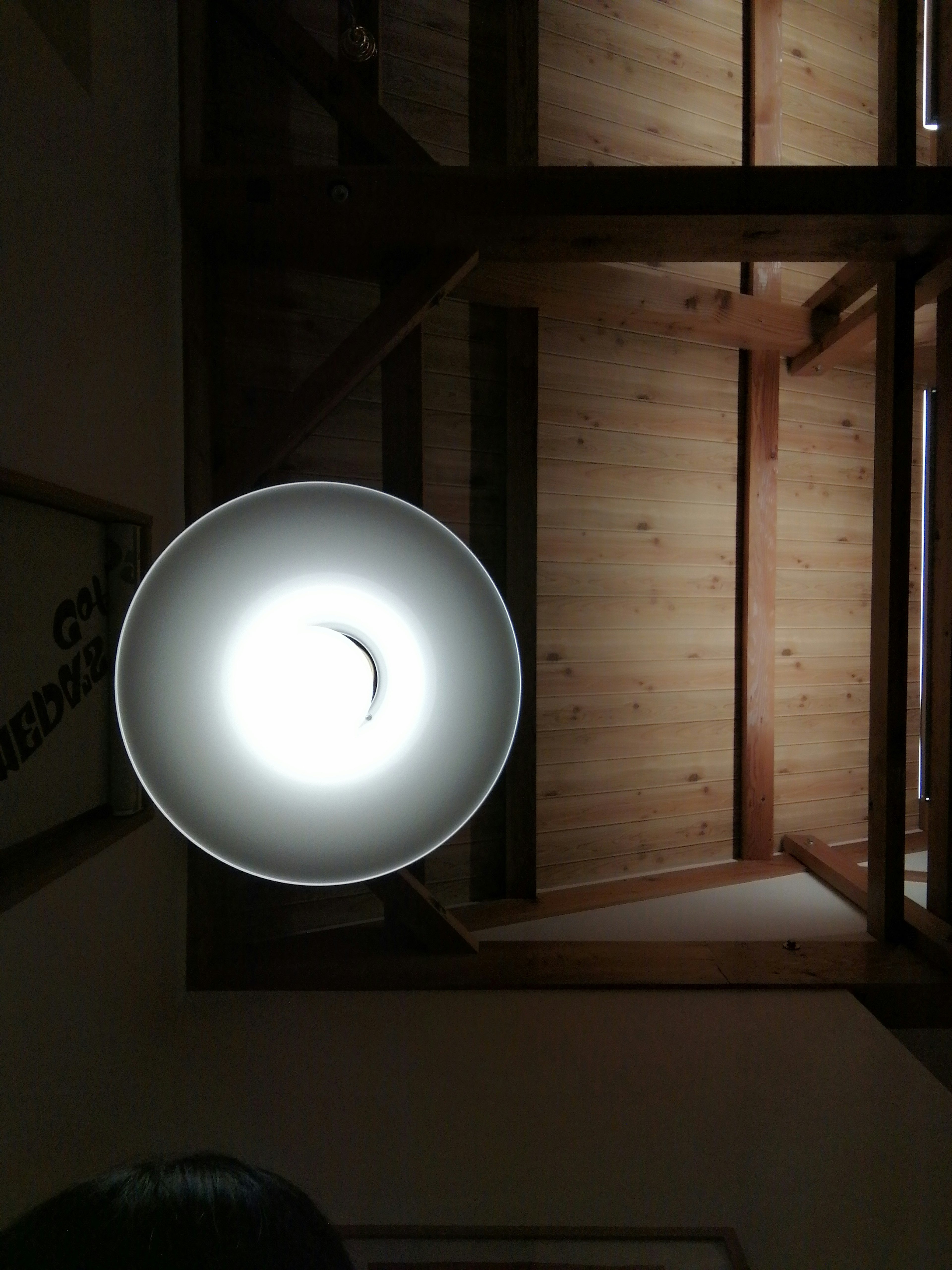 Vista interna dal basso con un apparecchio di illuminazione e un soffitto in legno