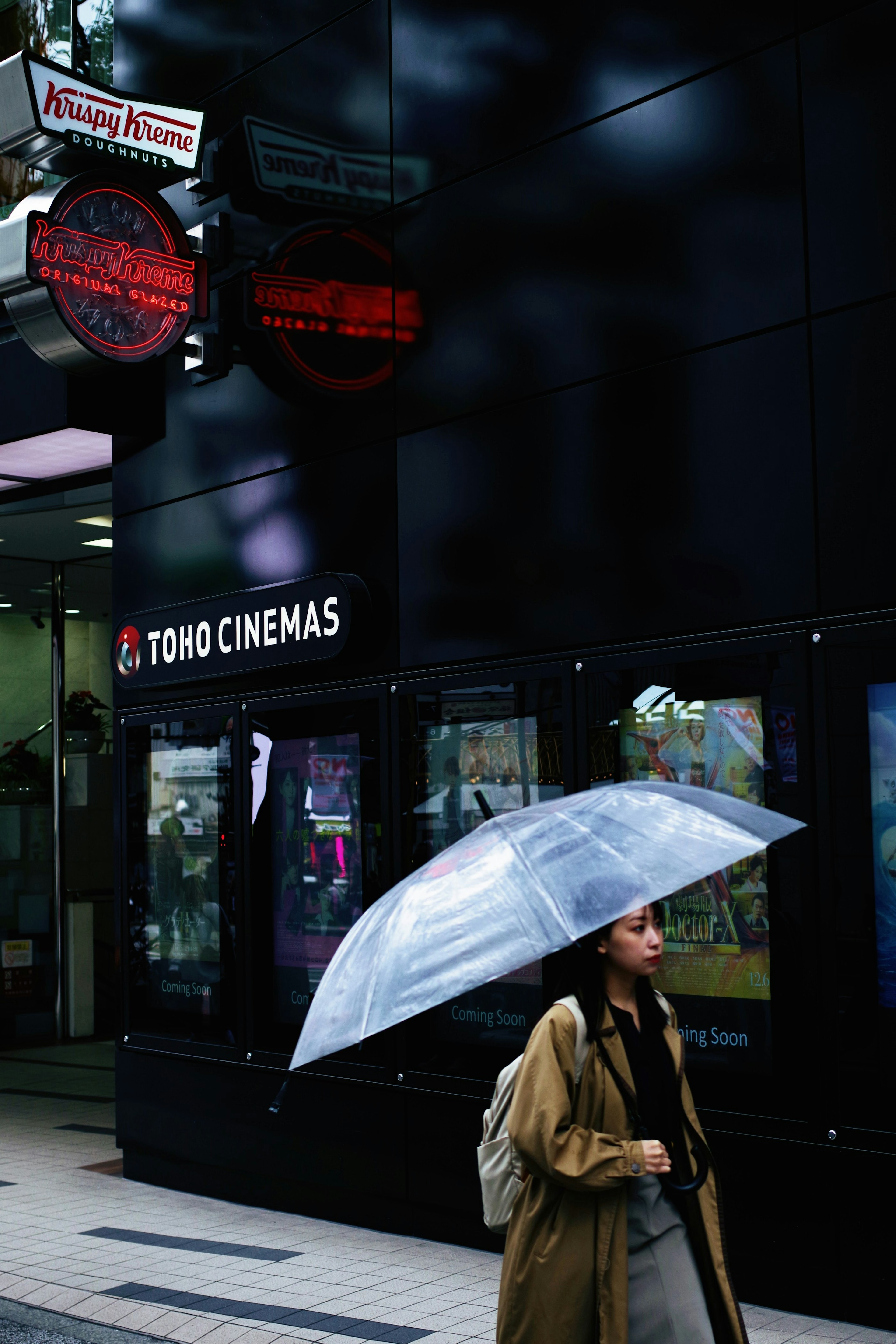 Donna che cammina davanti a TOHO Cinemas con un ombrello trasparente