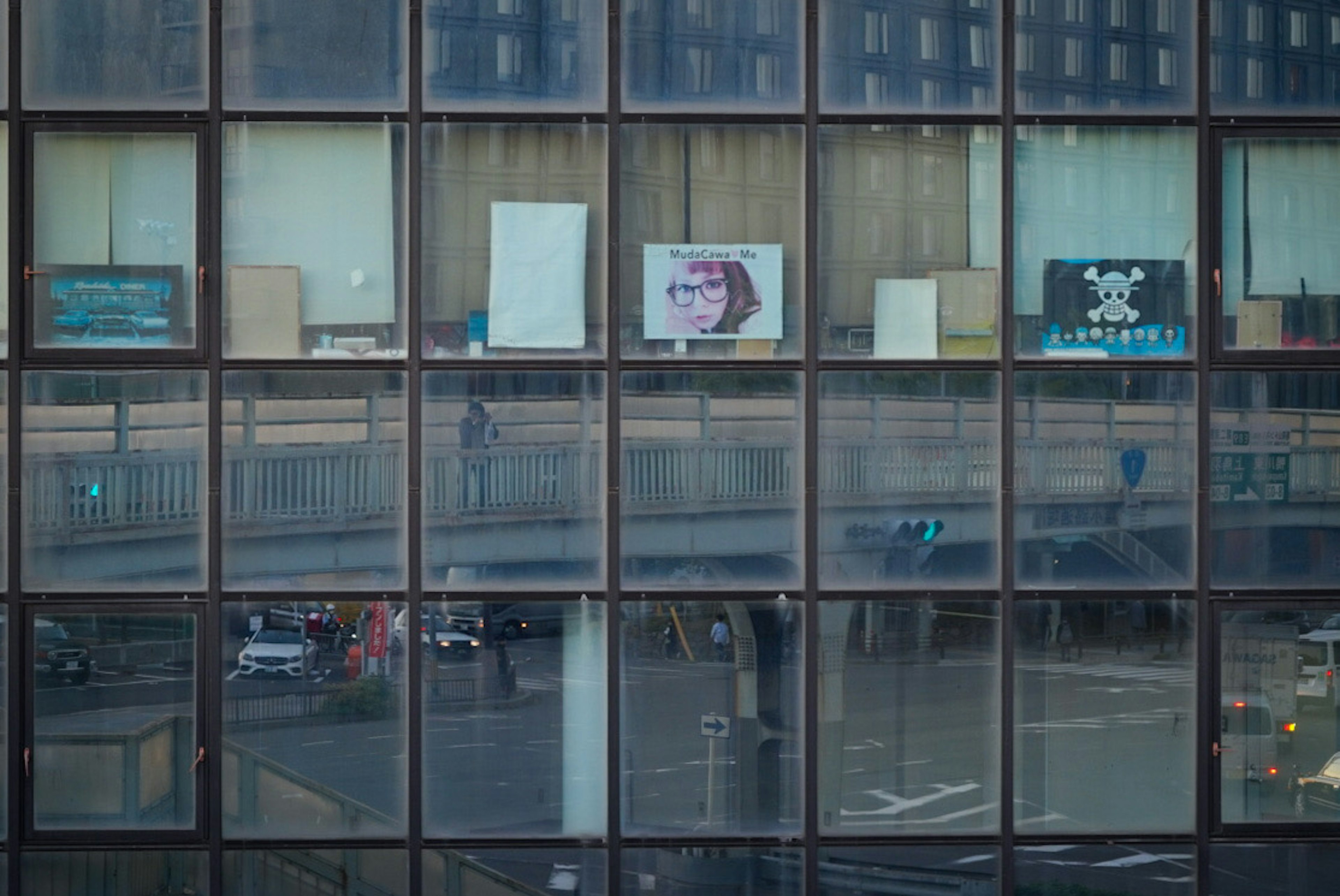 Gebäudefassade mit Glasfenstern, die die städtische Landschaft und Werbung reflektieren