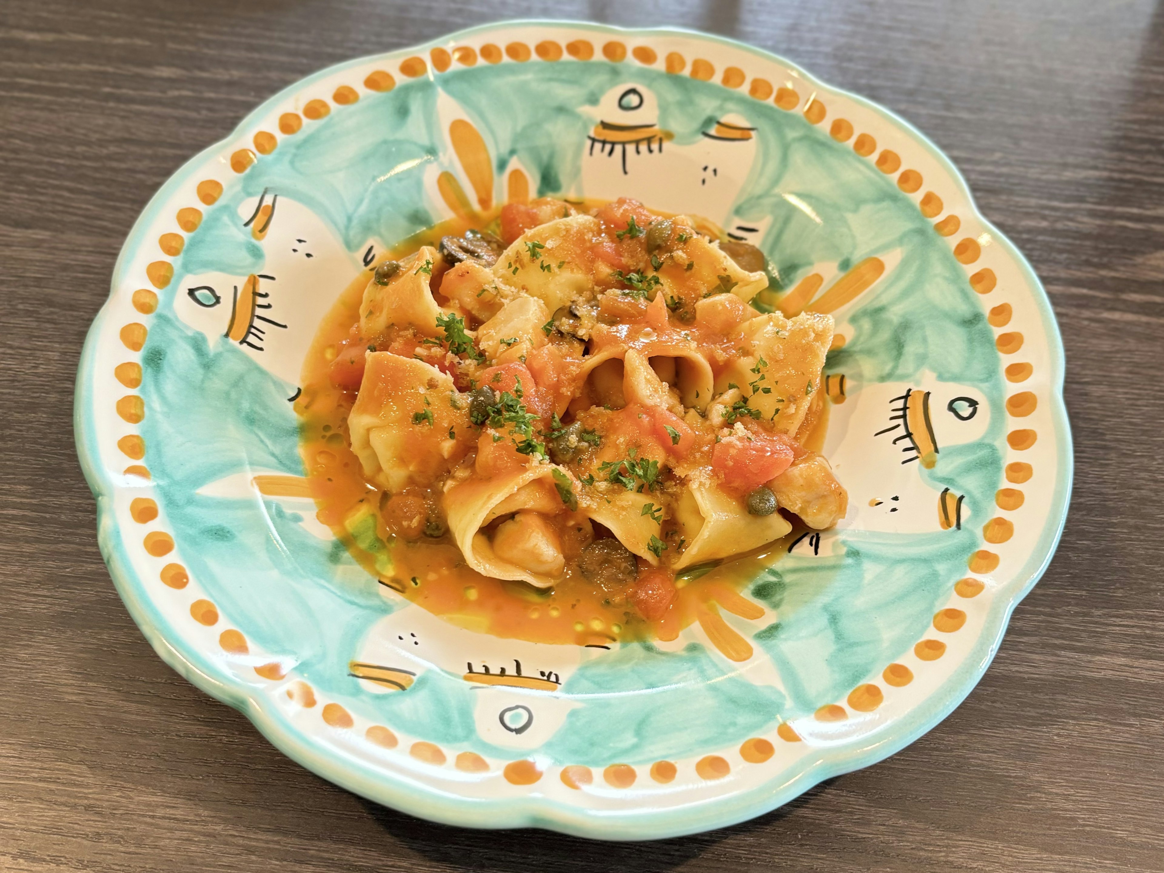 Assiette colorée avec un plat de pâtes garni d'herbes et de sauce