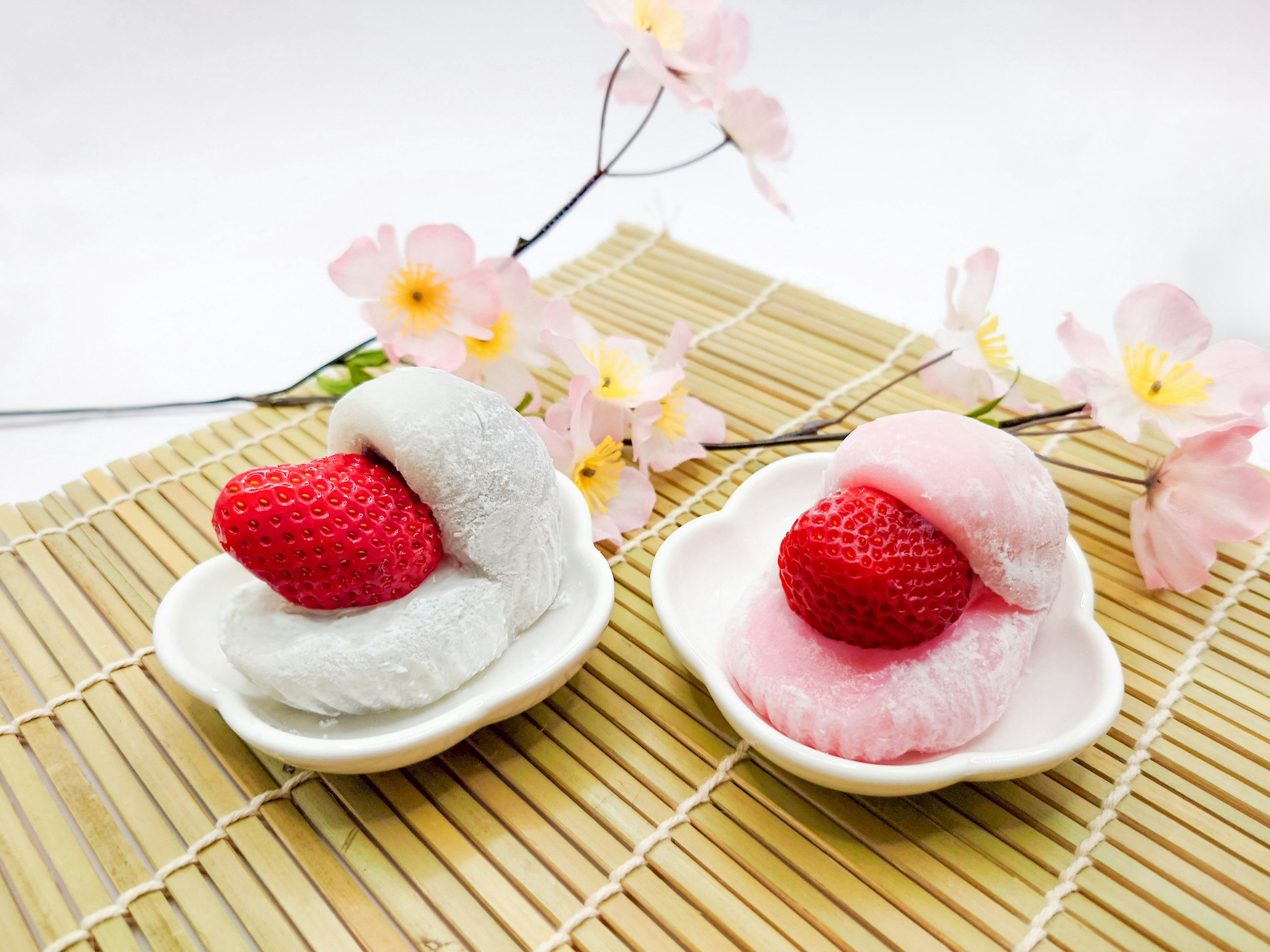 Desserts japonais avec des fraises sur de la mochi blanche et rose servis dans une assiette décorative