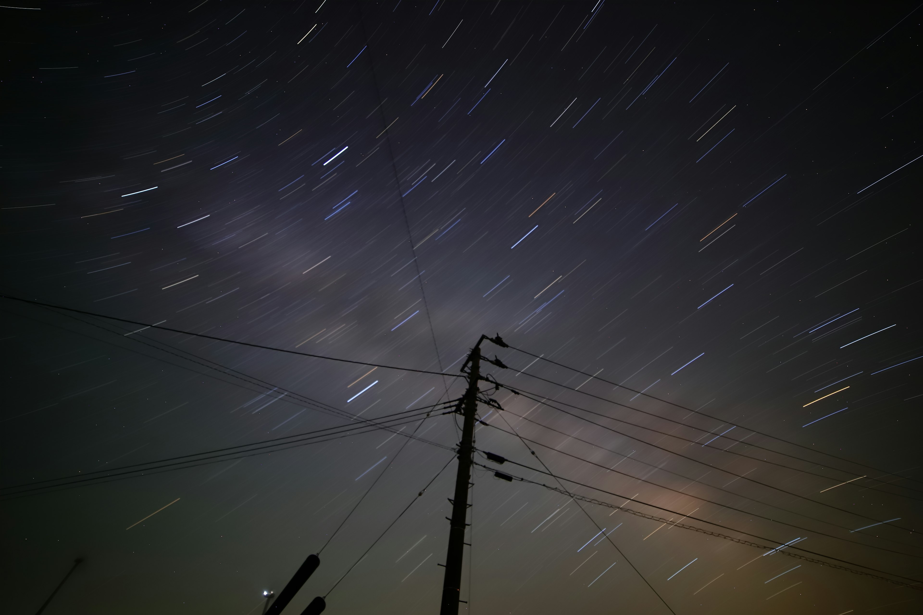 星の軌跡と電柱が映る夜空の写真