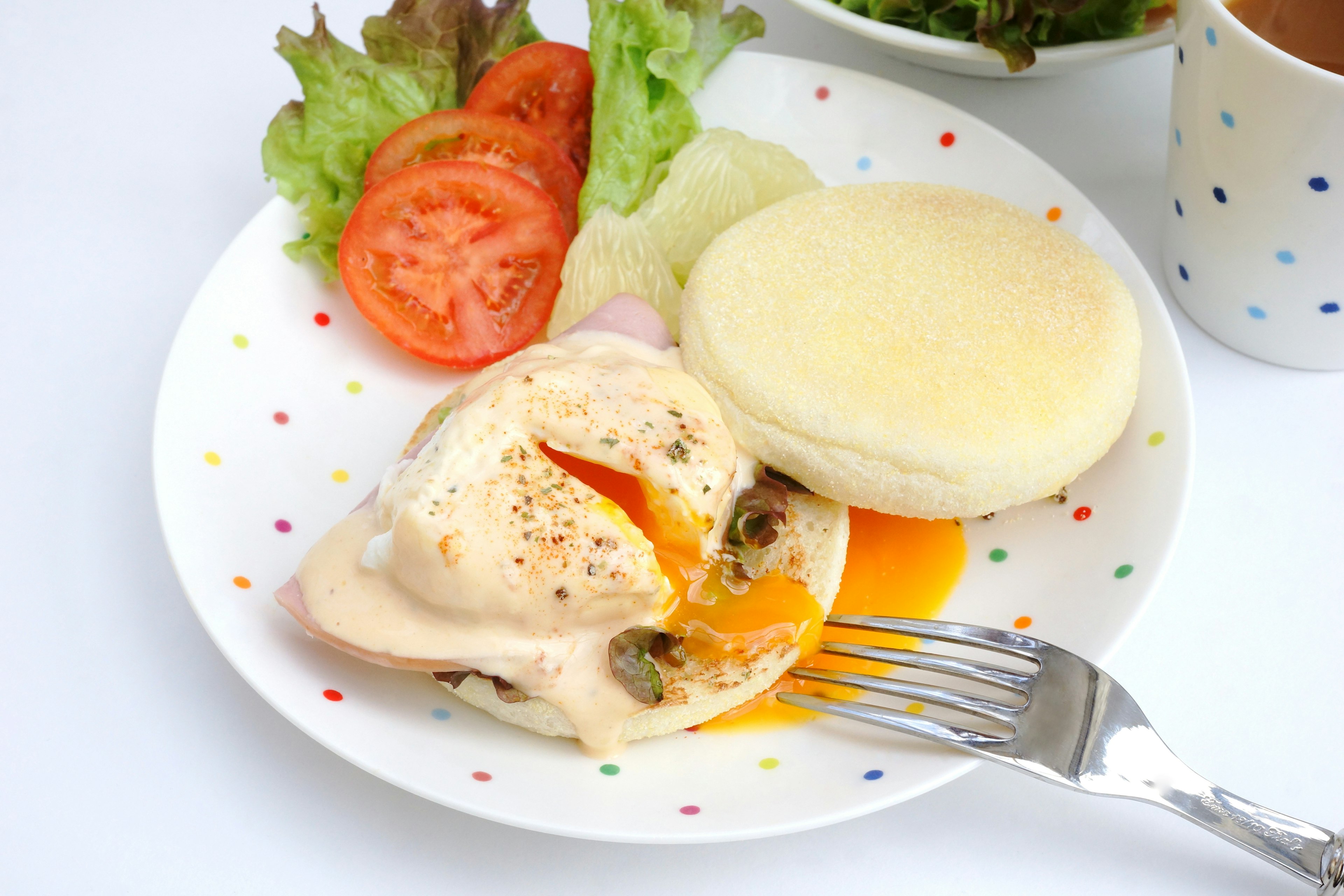 Telur benedict disajikan di piring dengan salad dan irisan tomat