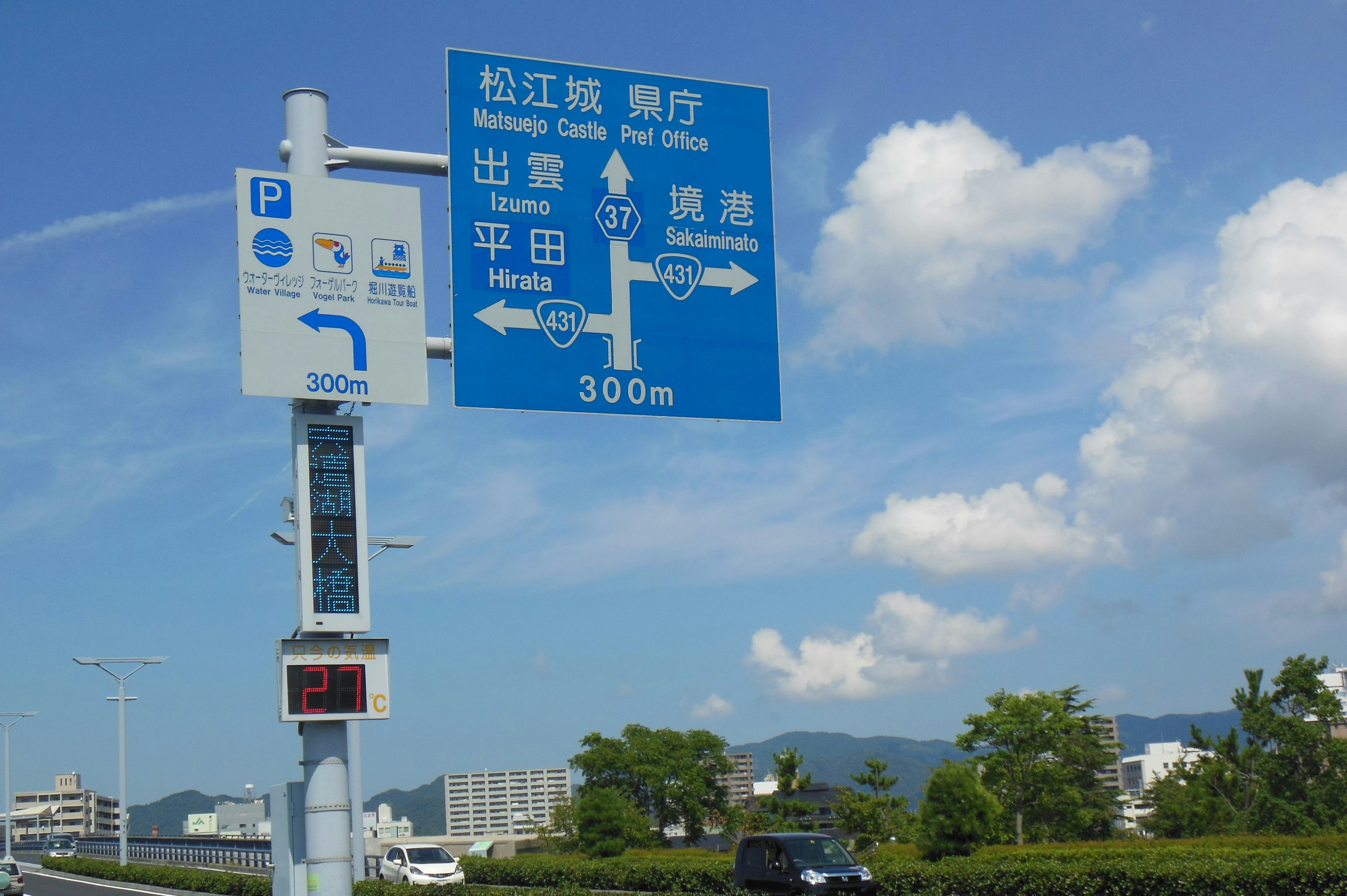 Segnale stradale blu che indica le direzioni per Matsue Onsen con distanze