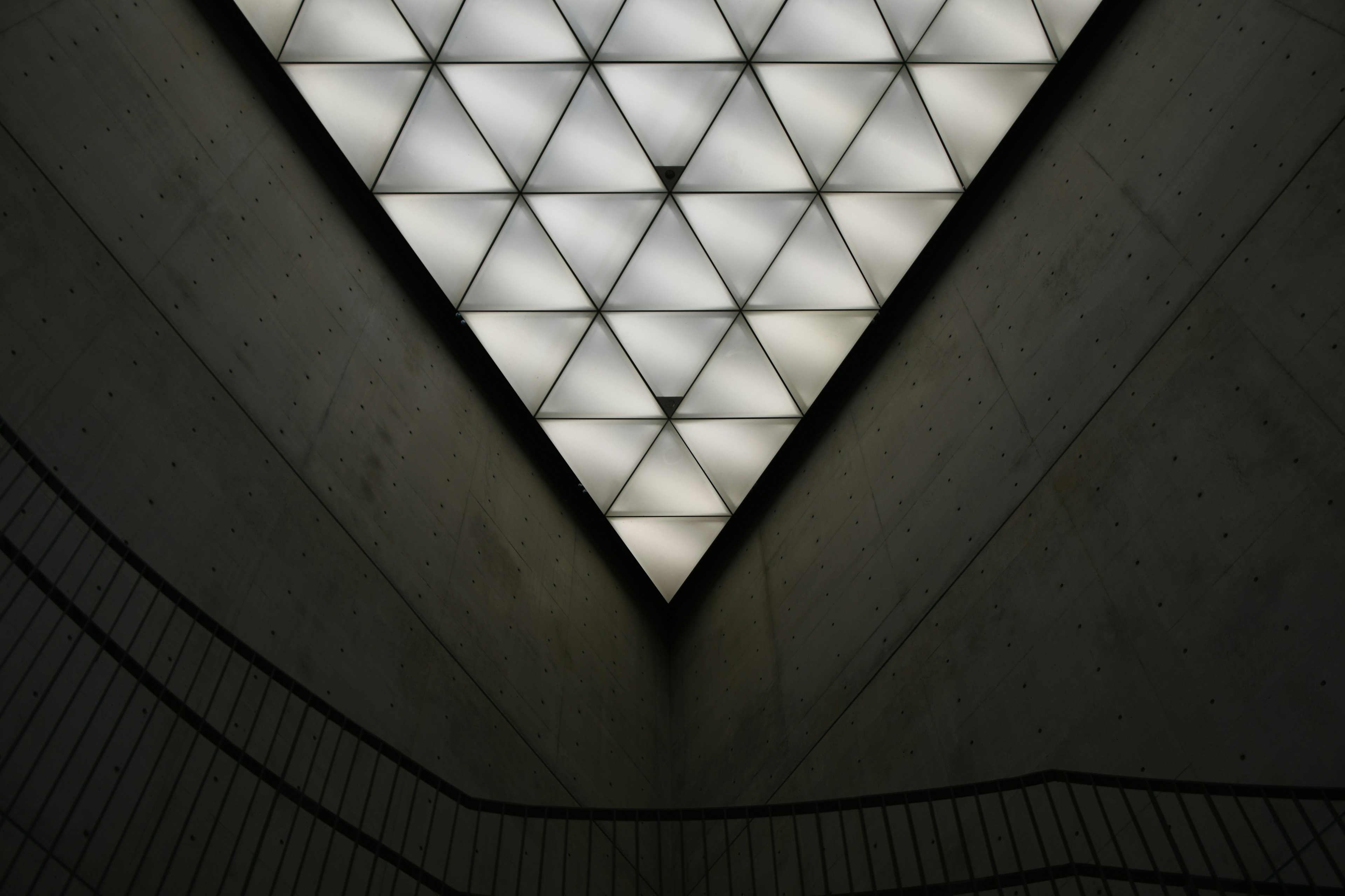 Interior view of a modern space with a triangular ceiling featuring illuminated geometric patterns