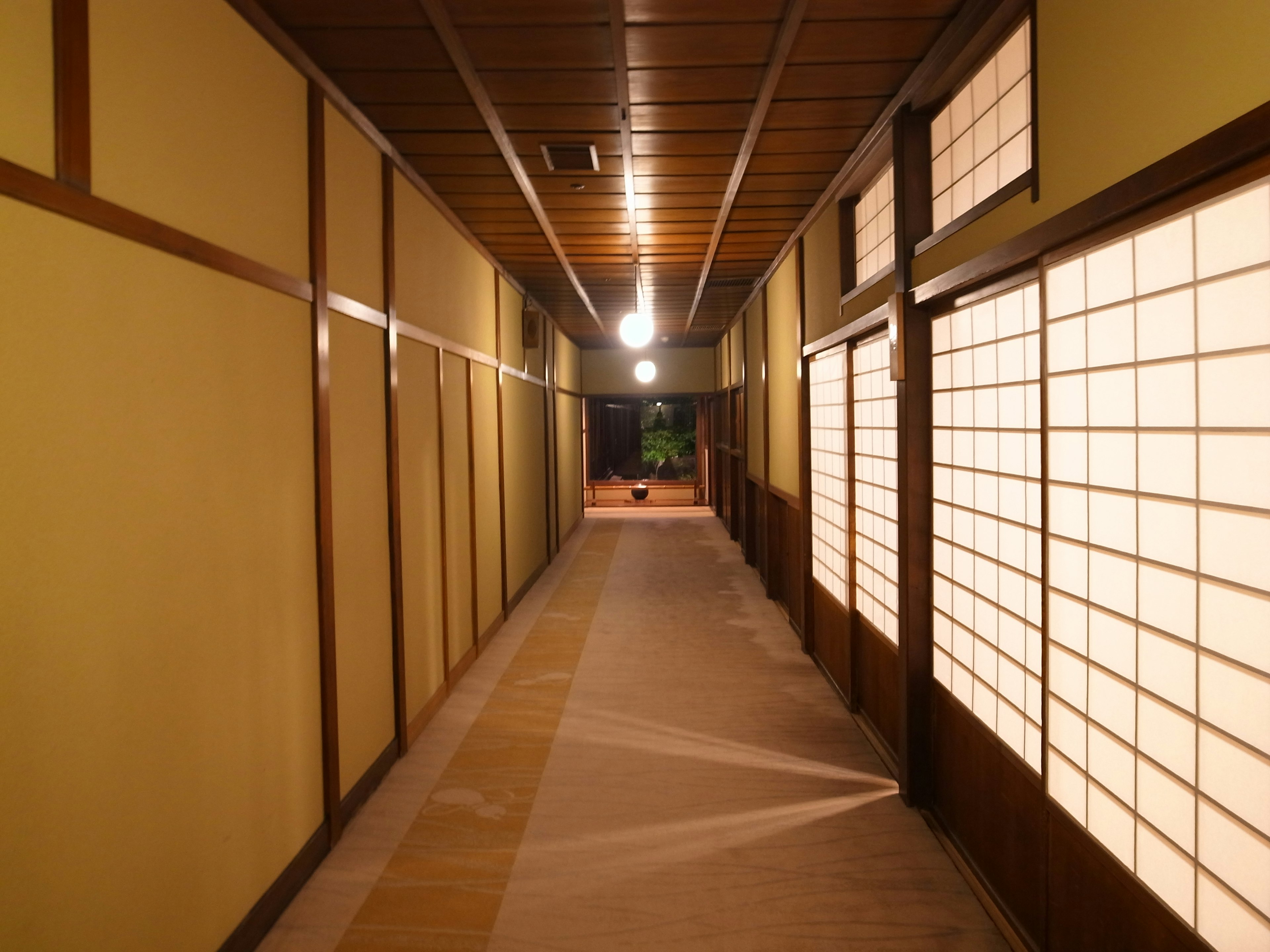 Lungo corridoio giapponese sereno con illuminazione soffusa pavimento in tatami e pareti in shoji