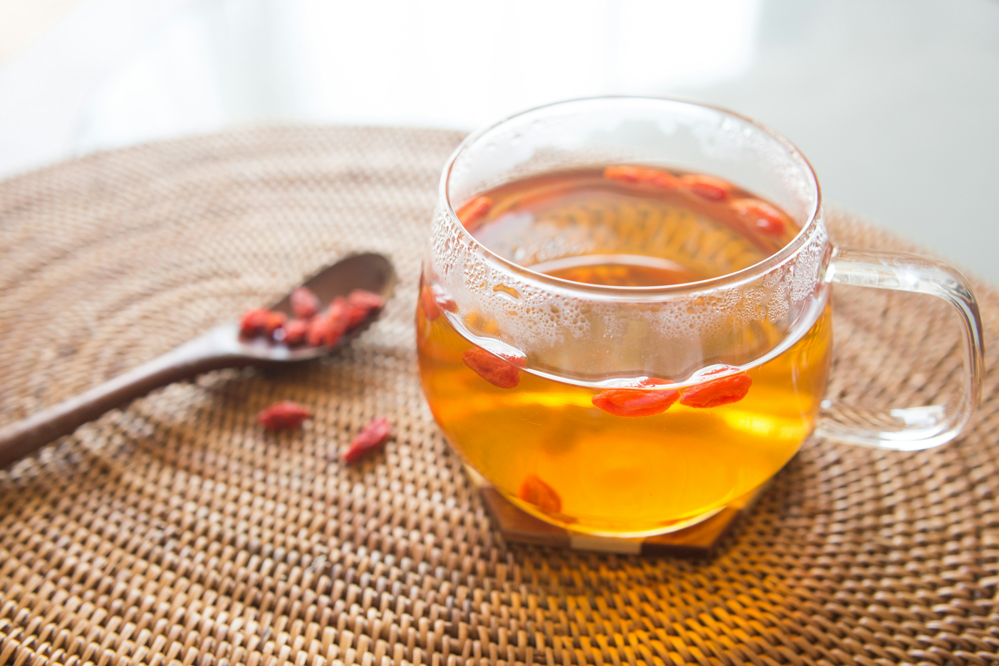 Tasse en verre de thé aux baies de goji et cuillère en bois