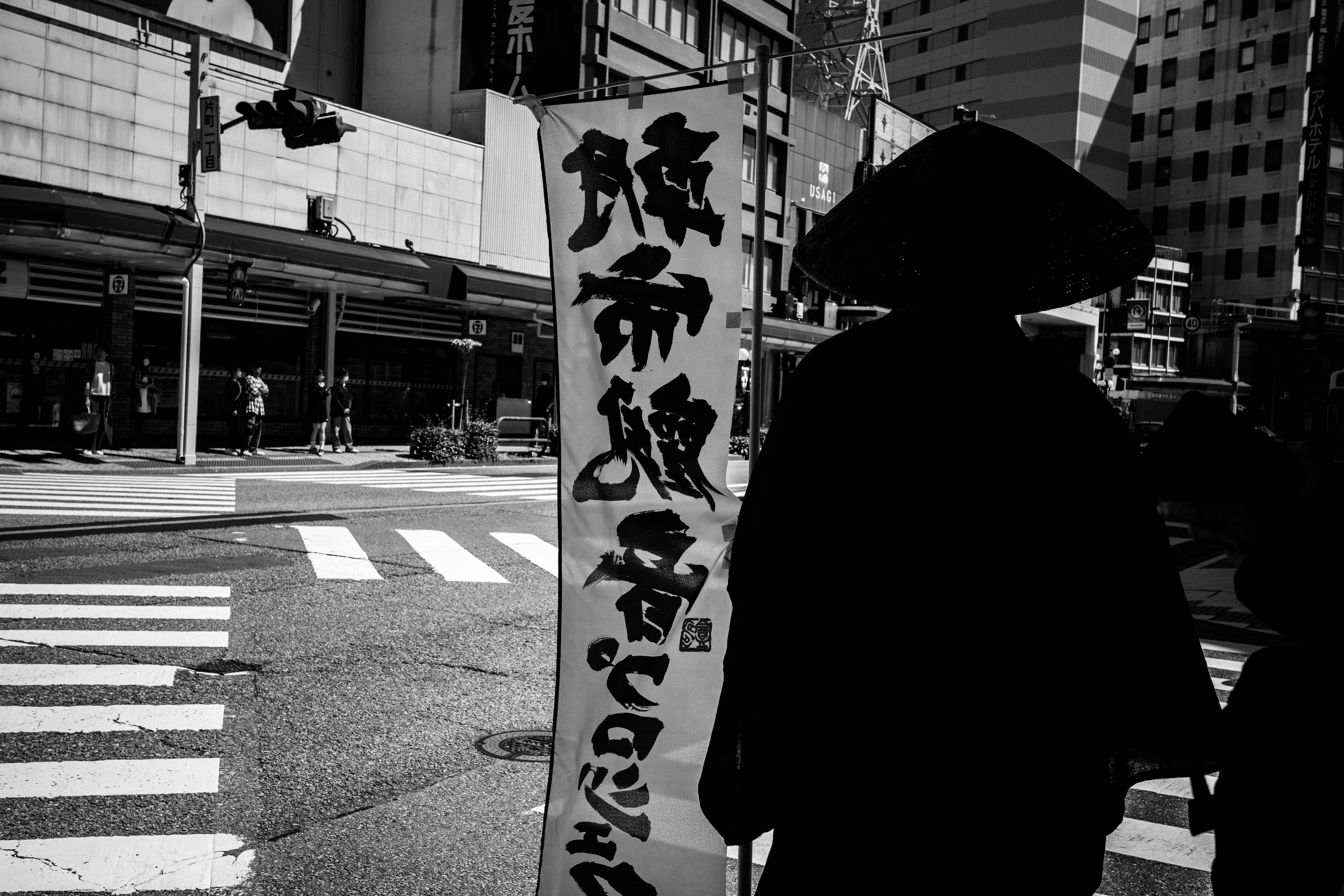 Silhouette of a person standing at a street corner with high-rise buildings in the background