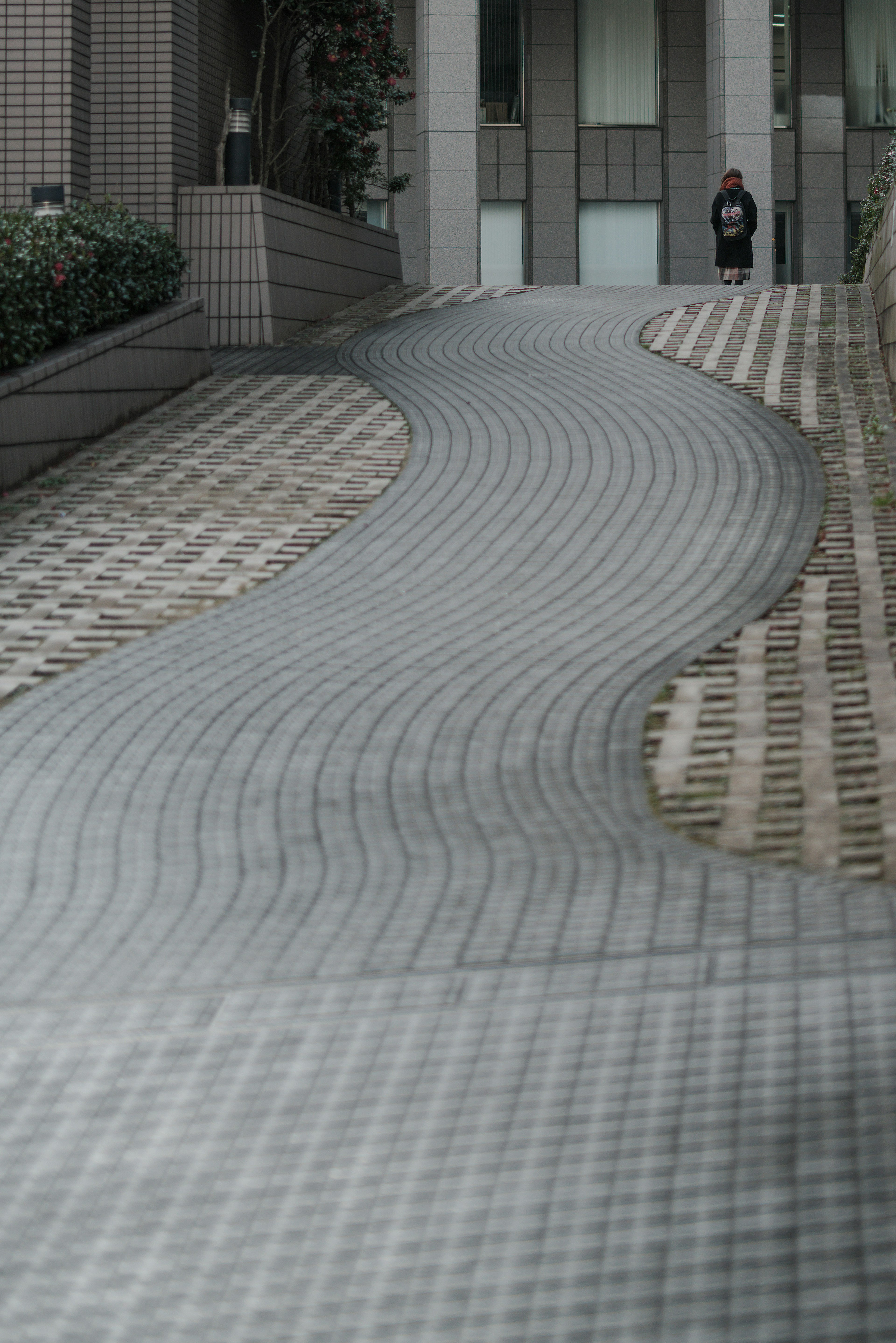 Curved tiled walkway with a person standing