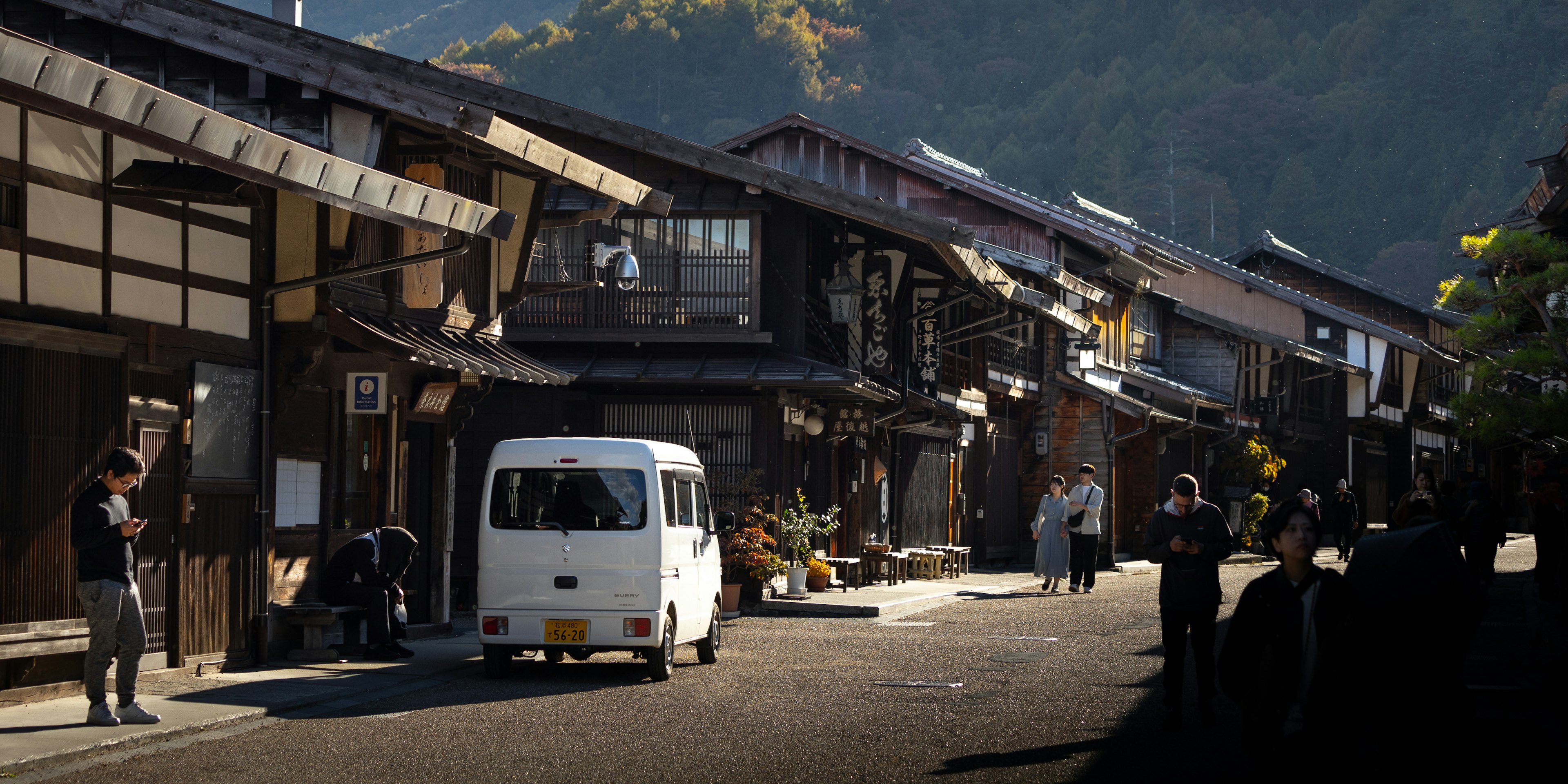 古い日本の街並みと白いバンが通る風景