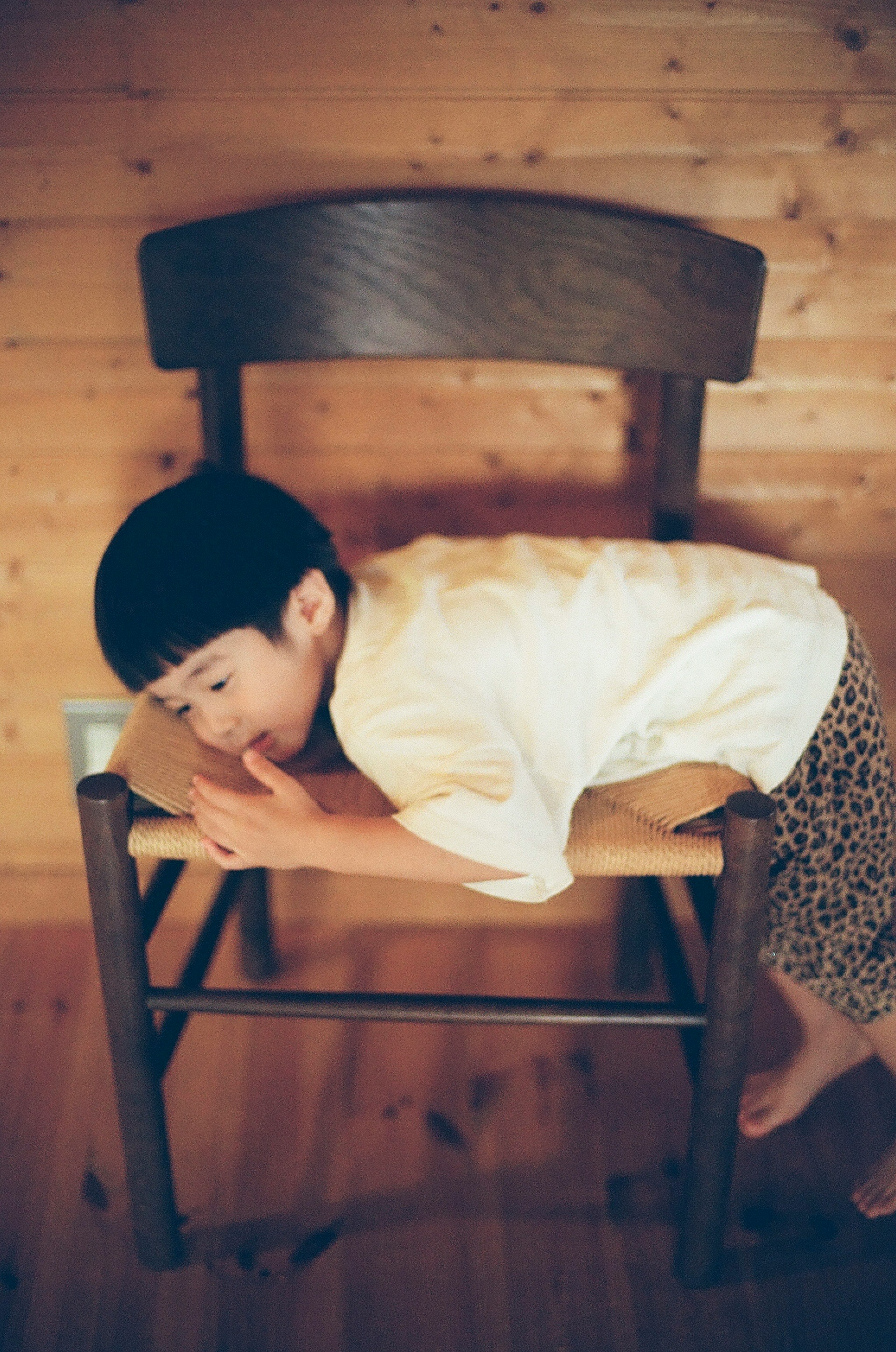 A child lying on a wooden chair in a cozy interior