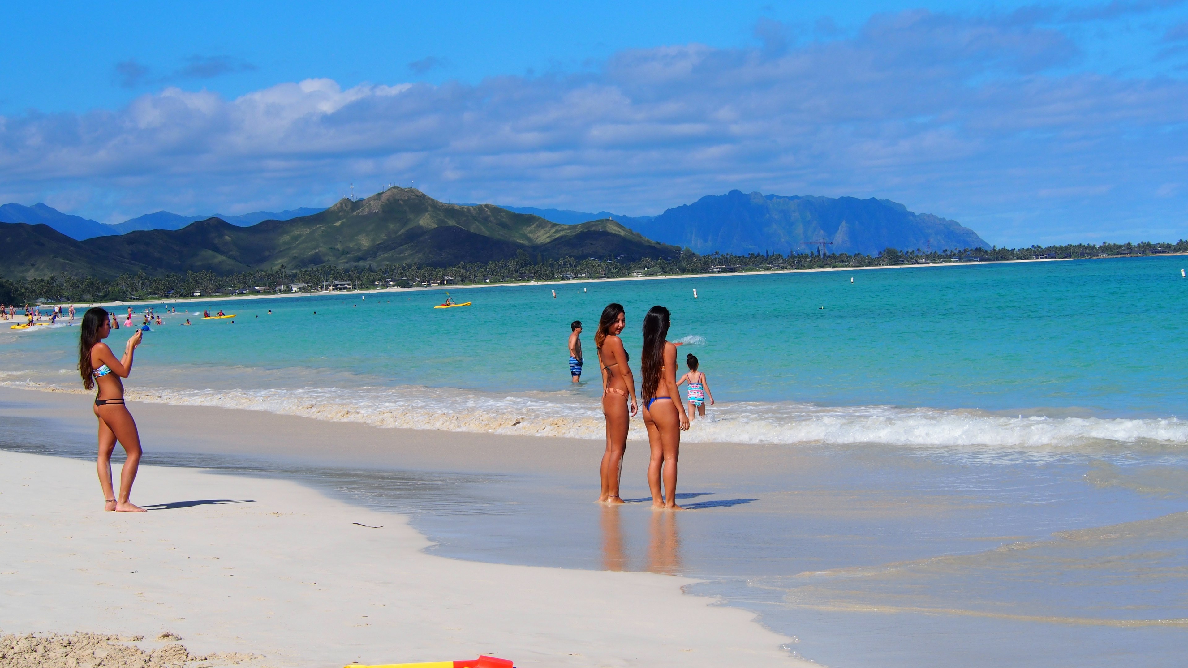 Personnes s'amusant à la plage avec mer bleue et sable blanc montagnes en arrière-plan