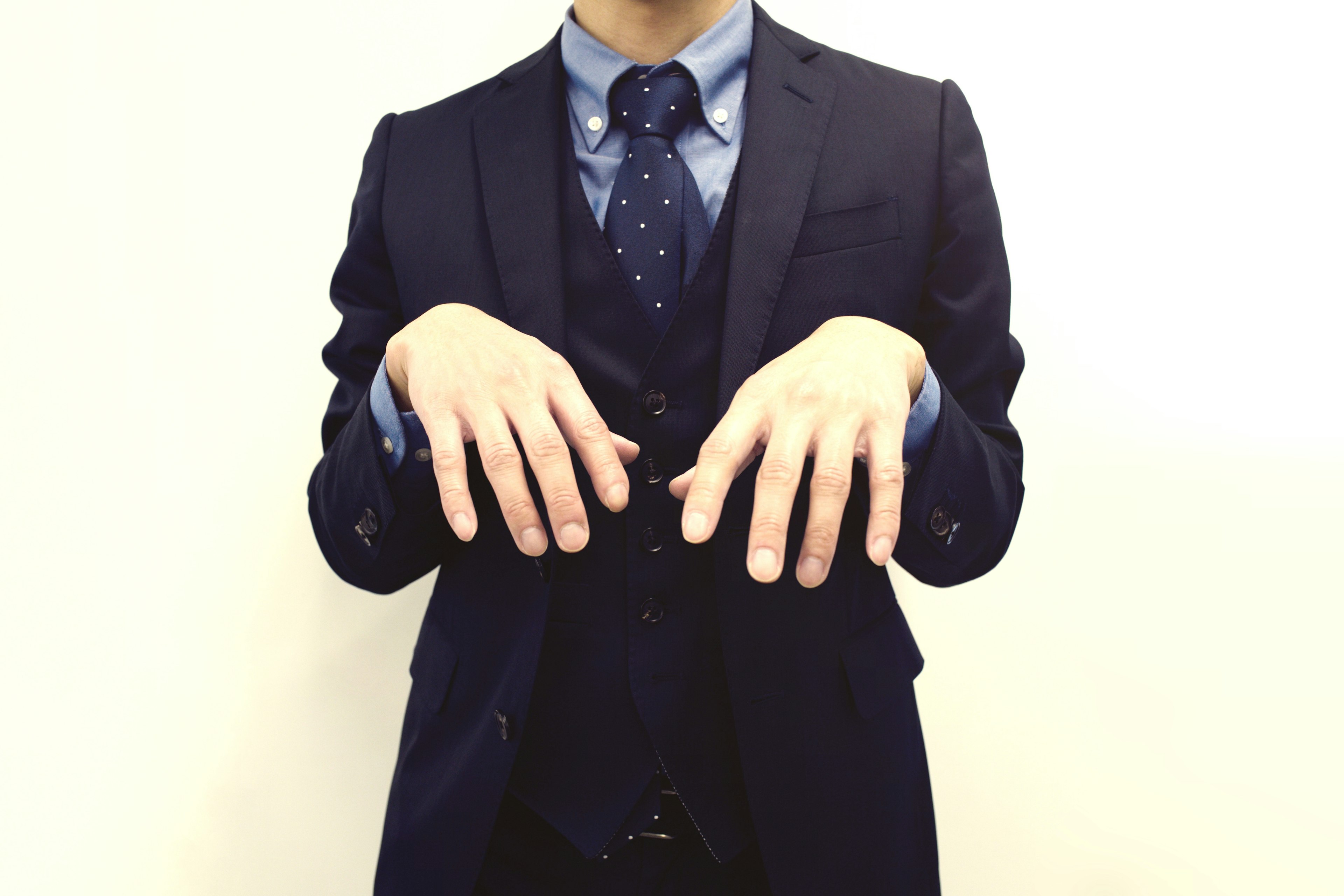 A man in a suit striking a playful pose with his hands