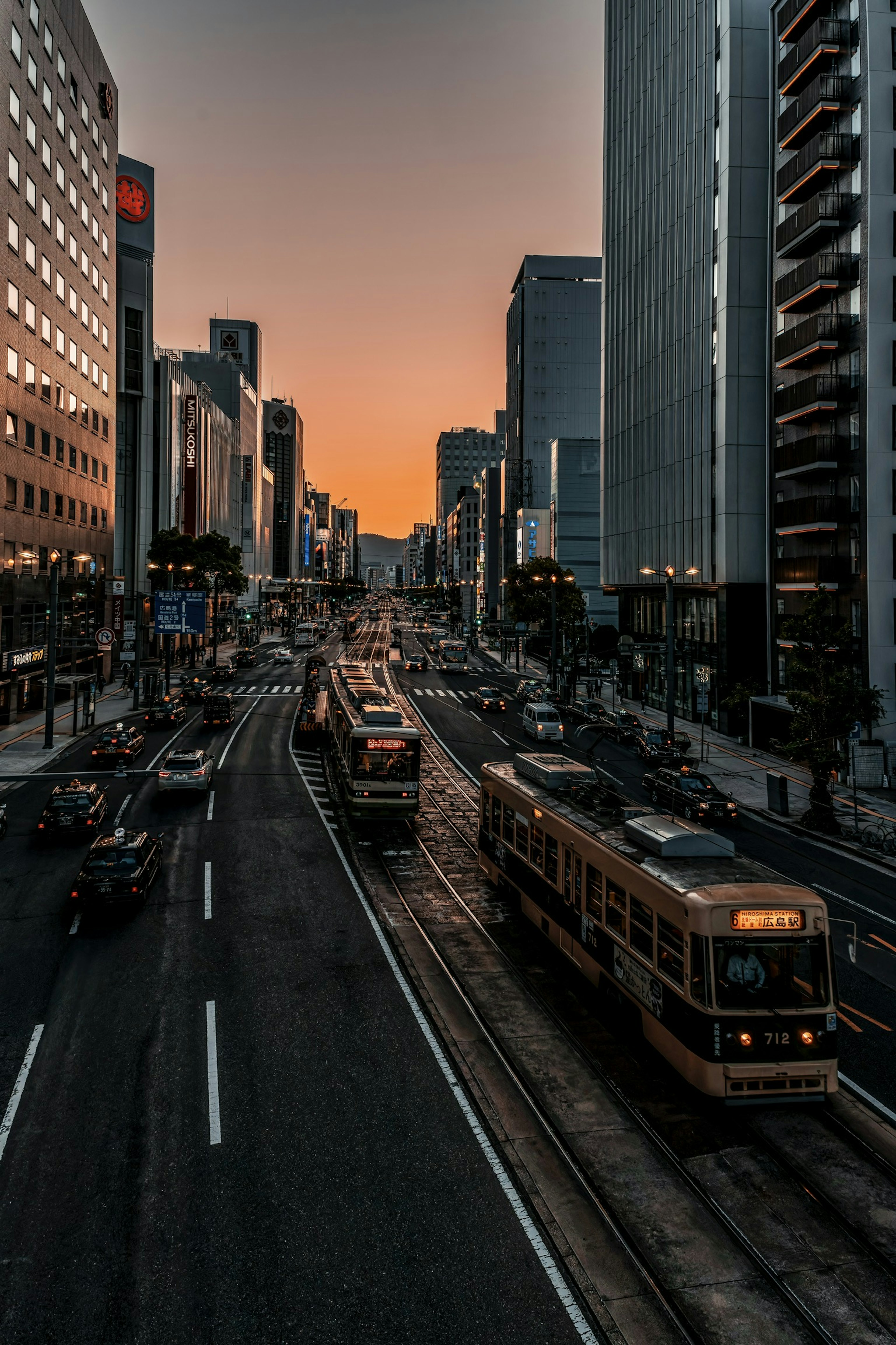 Stadtbild mit Straßenbahnen und Wolkenkratzern bei Sonnenuntergang