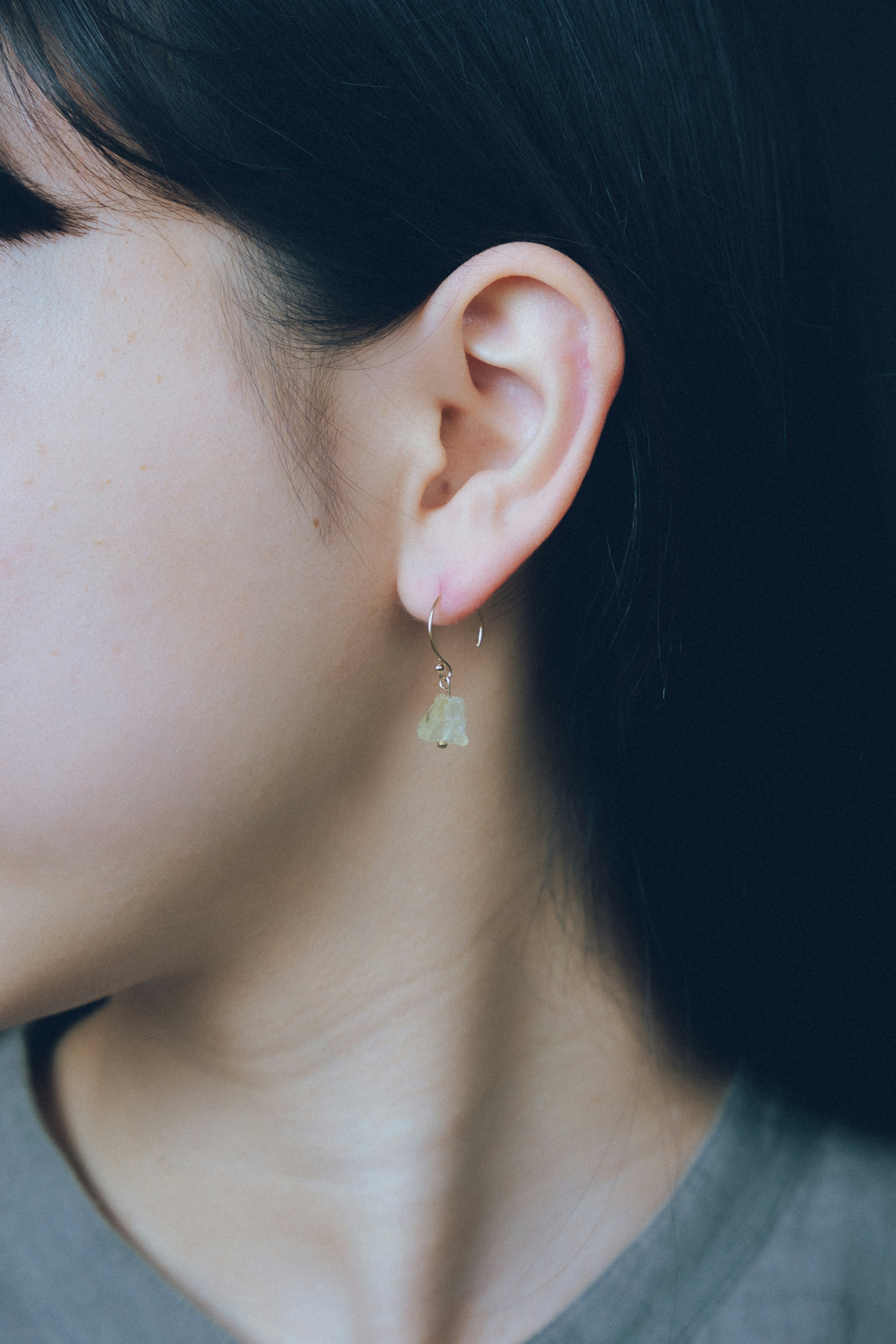 Profil latéral d'une femme portant une boucle d'oreille verte pendante