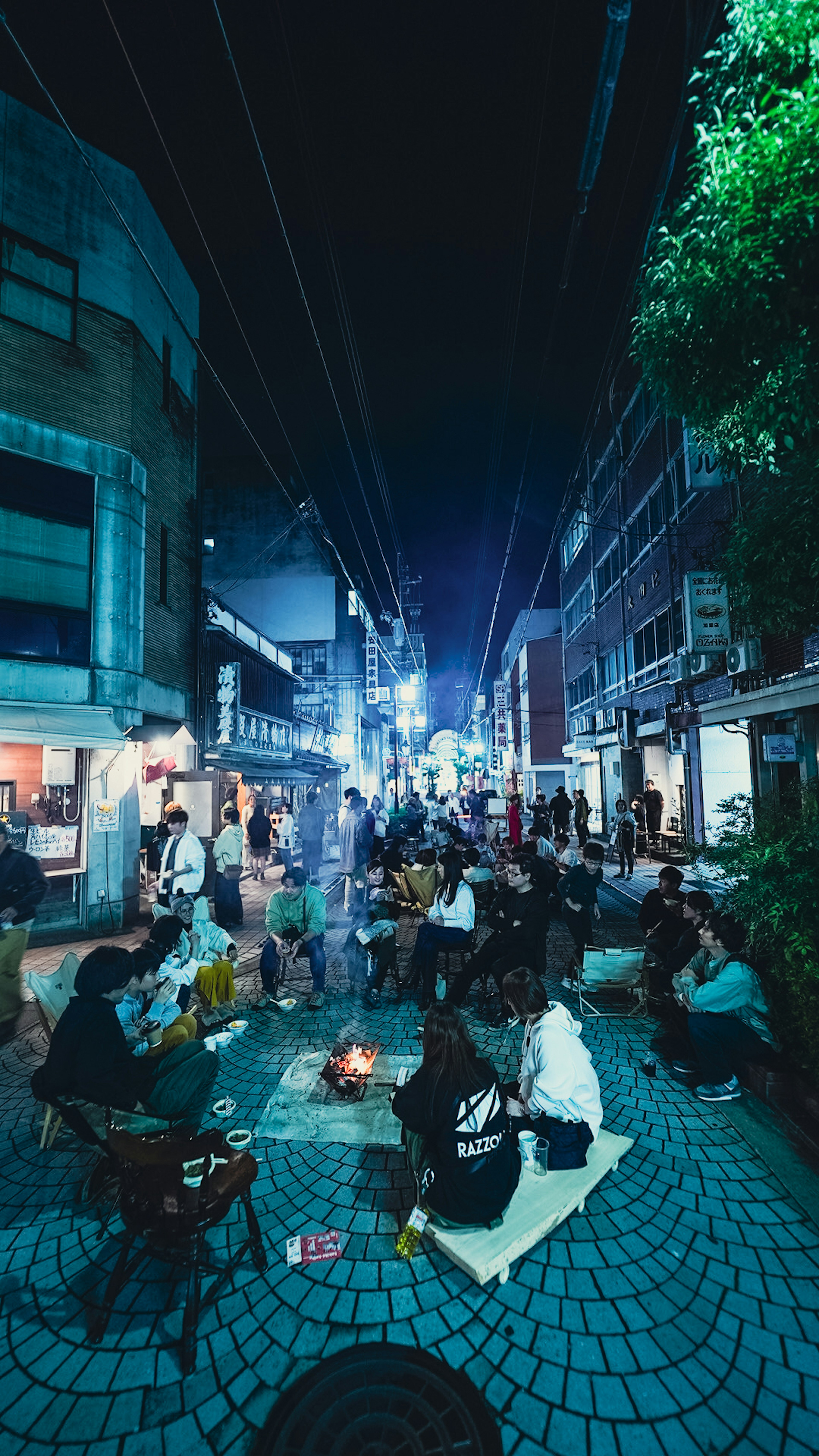 夜の街で集まる人々と小さな火がある風景