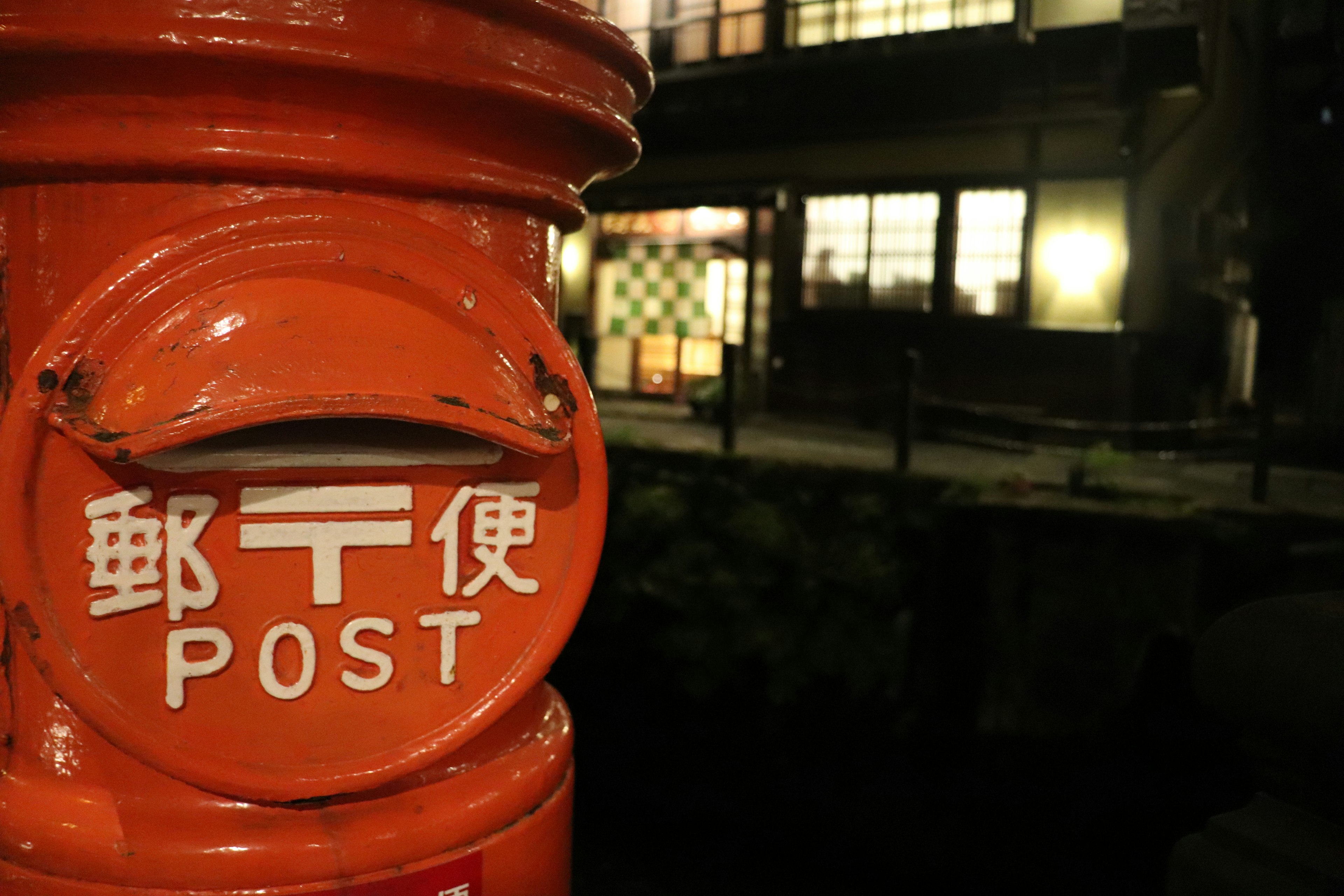 Oranger Briefkasten mit japanischen Schriftzeichen bei Nacht