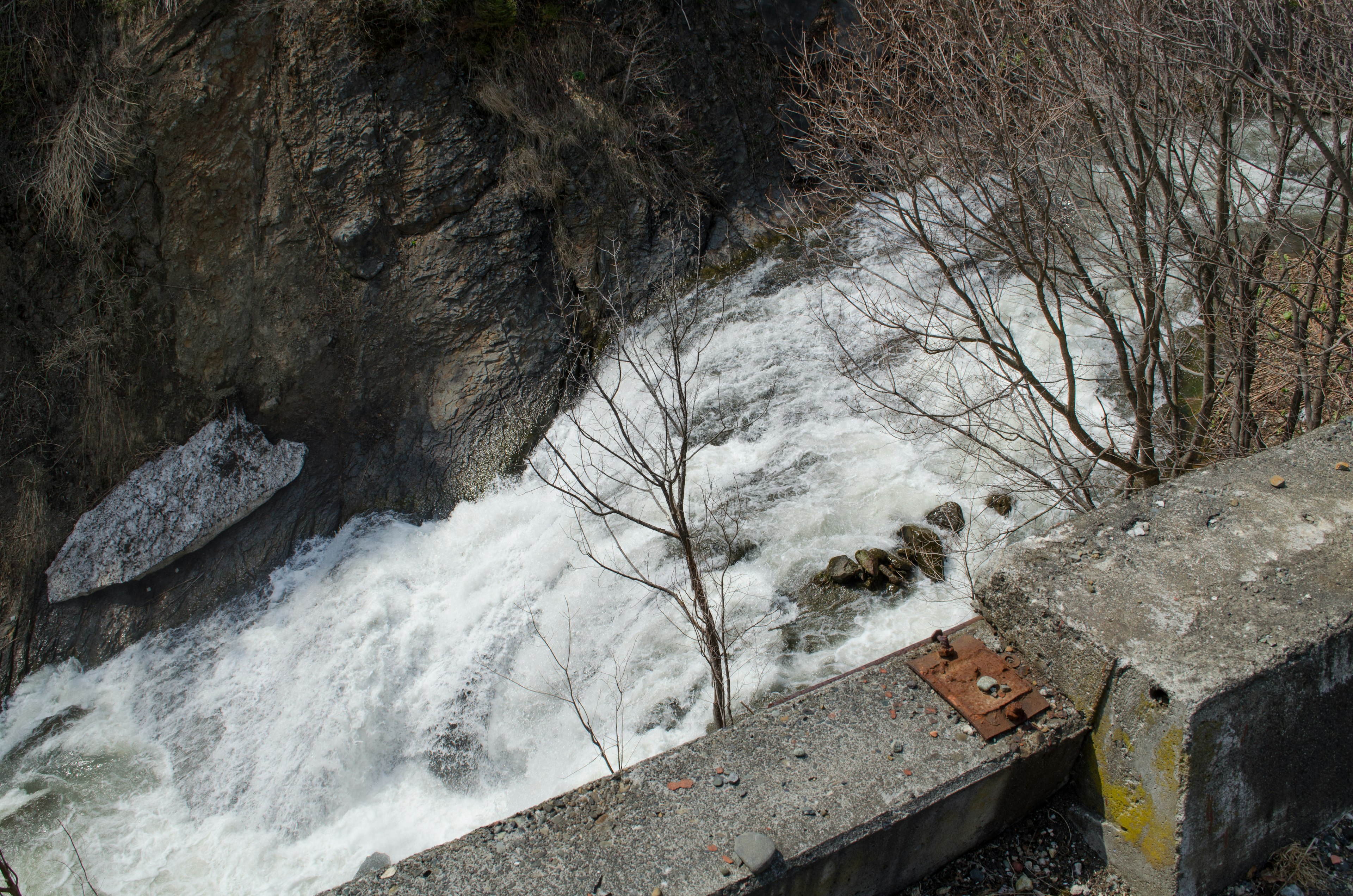 Malersicher Blick auf einen rauschenden Fluss neben einer Betonmauer