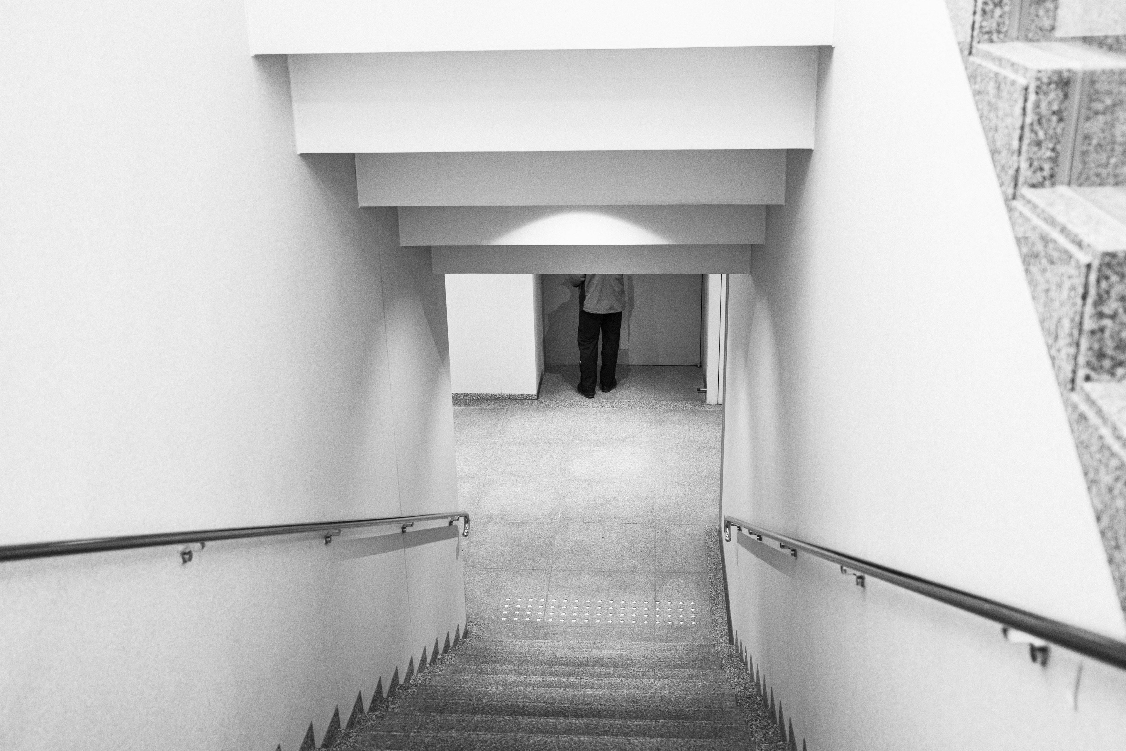 Black and white image of a person standing at the bottom of a staircase Simple design and bright lighting