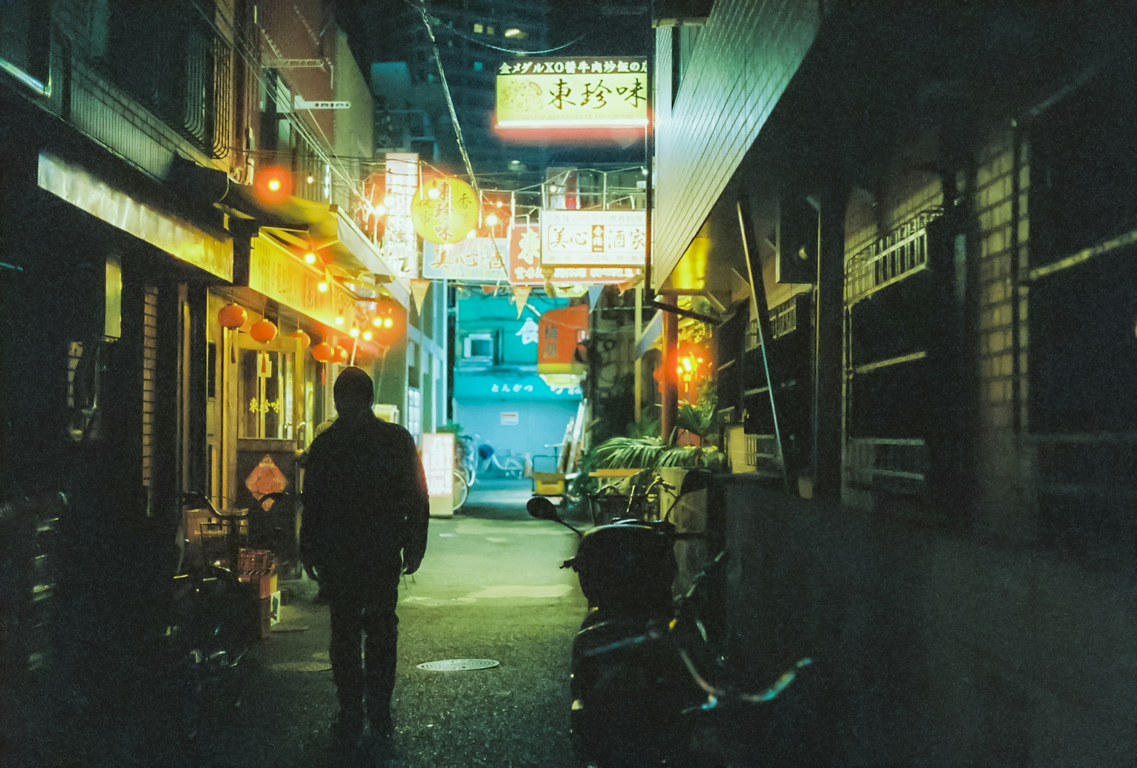 Une silhouette dans une ruelle sombre entourée de lanternes colorées la nuit