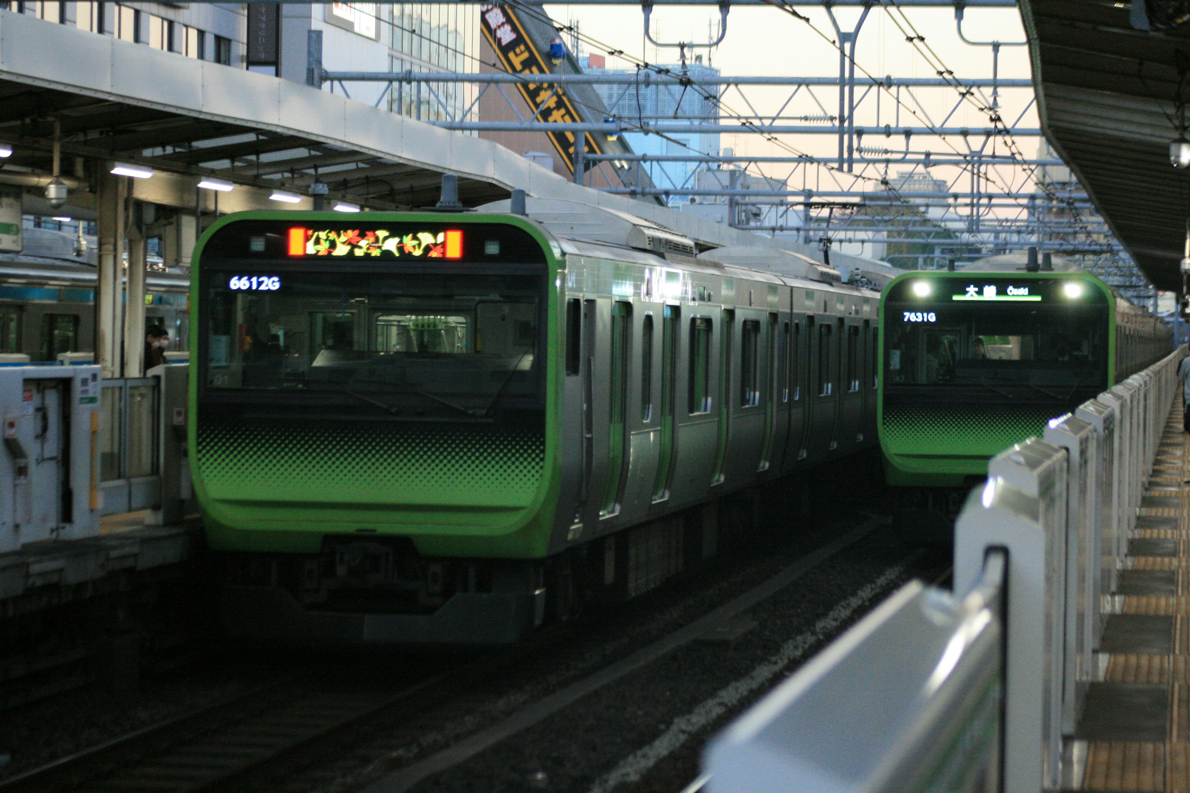 Green trains at a railway station during sunset