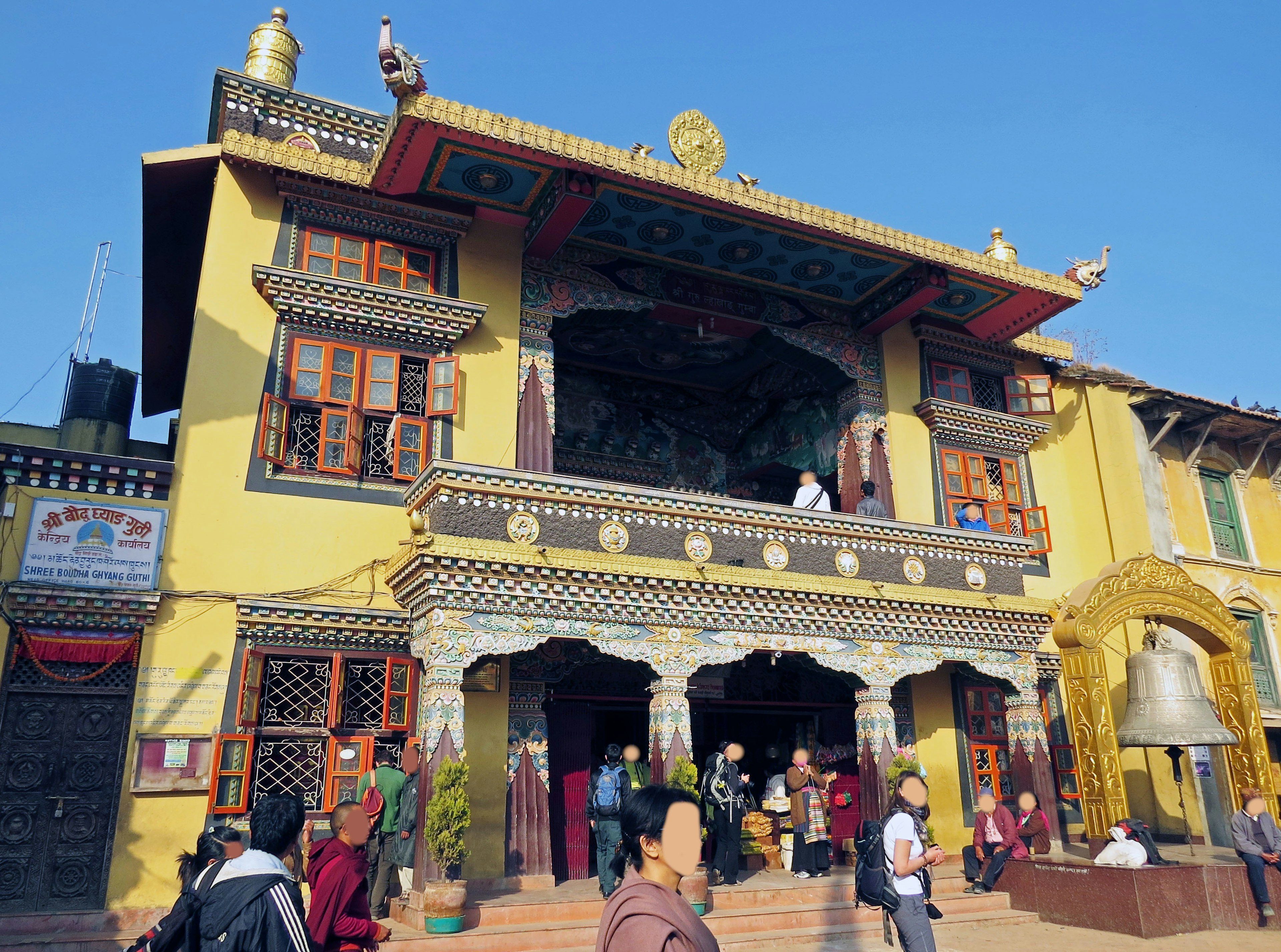 Extérieur coloré d'un temple tibétain sous un ciel bleu clair avec des visiteurs