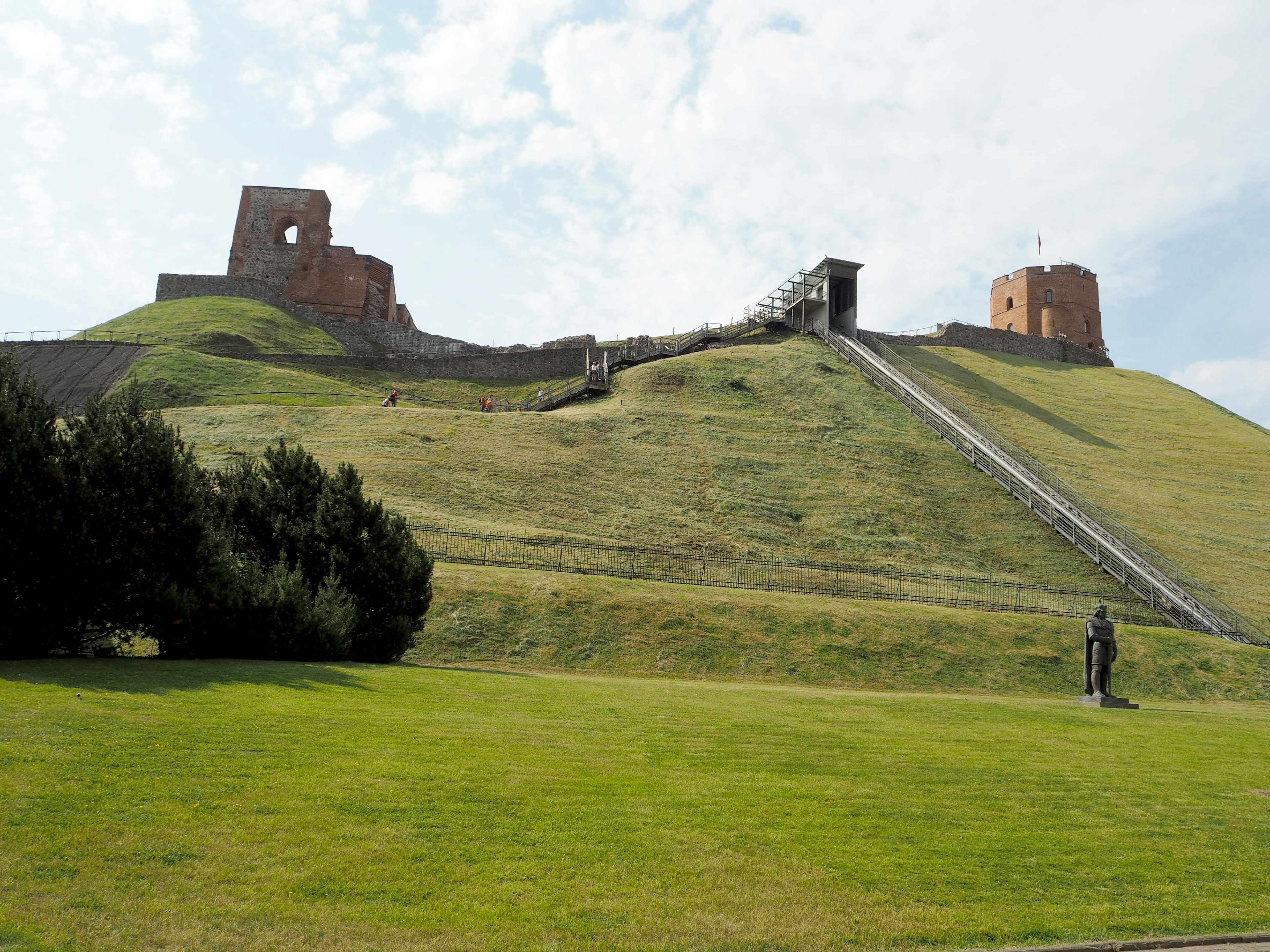 Rovine di un antico castello su una collina verde con cielo azzurro