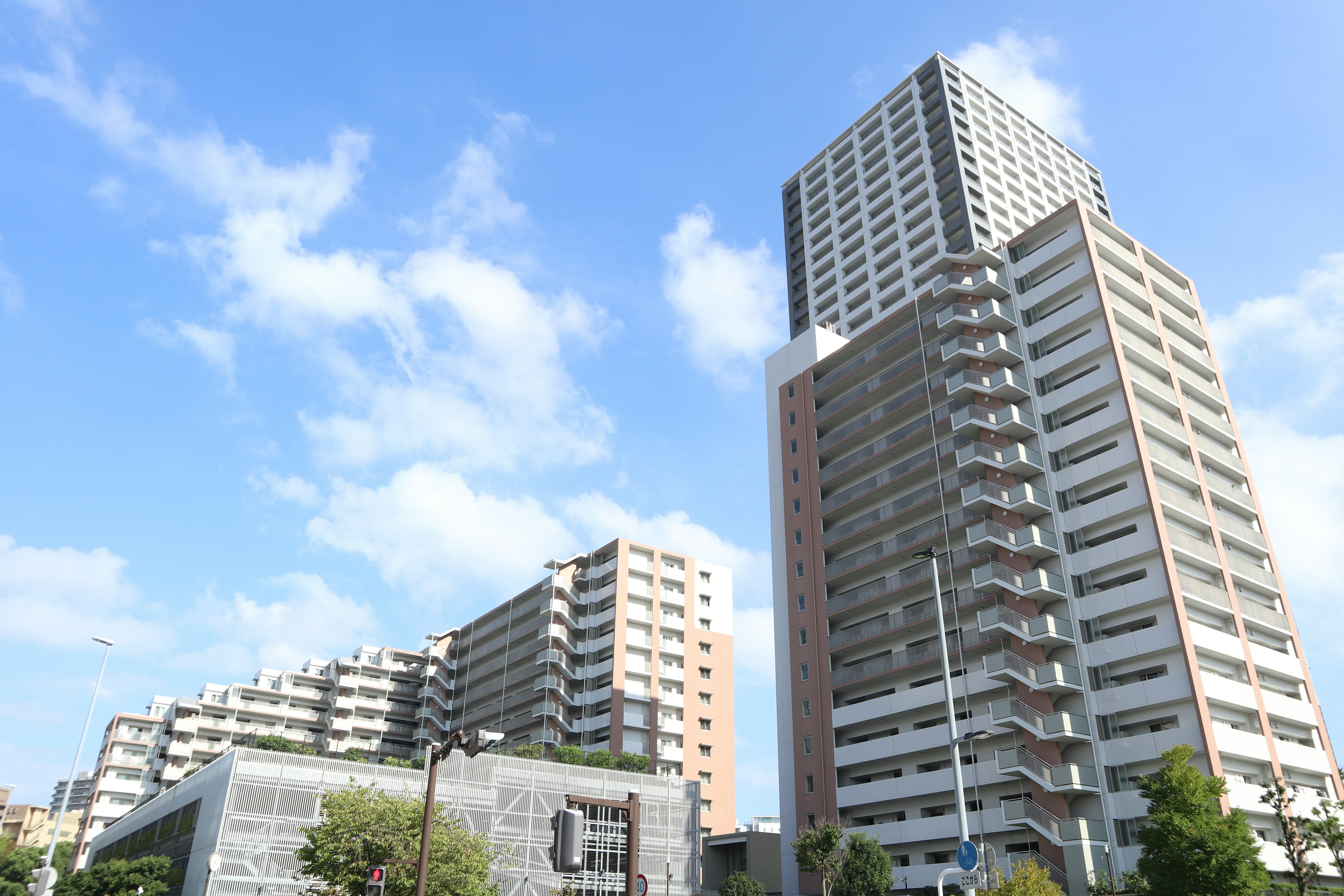 Paesaggio urbano con grattacieli e appartamenti residenziali sotto un cielo azzurro con nuvole