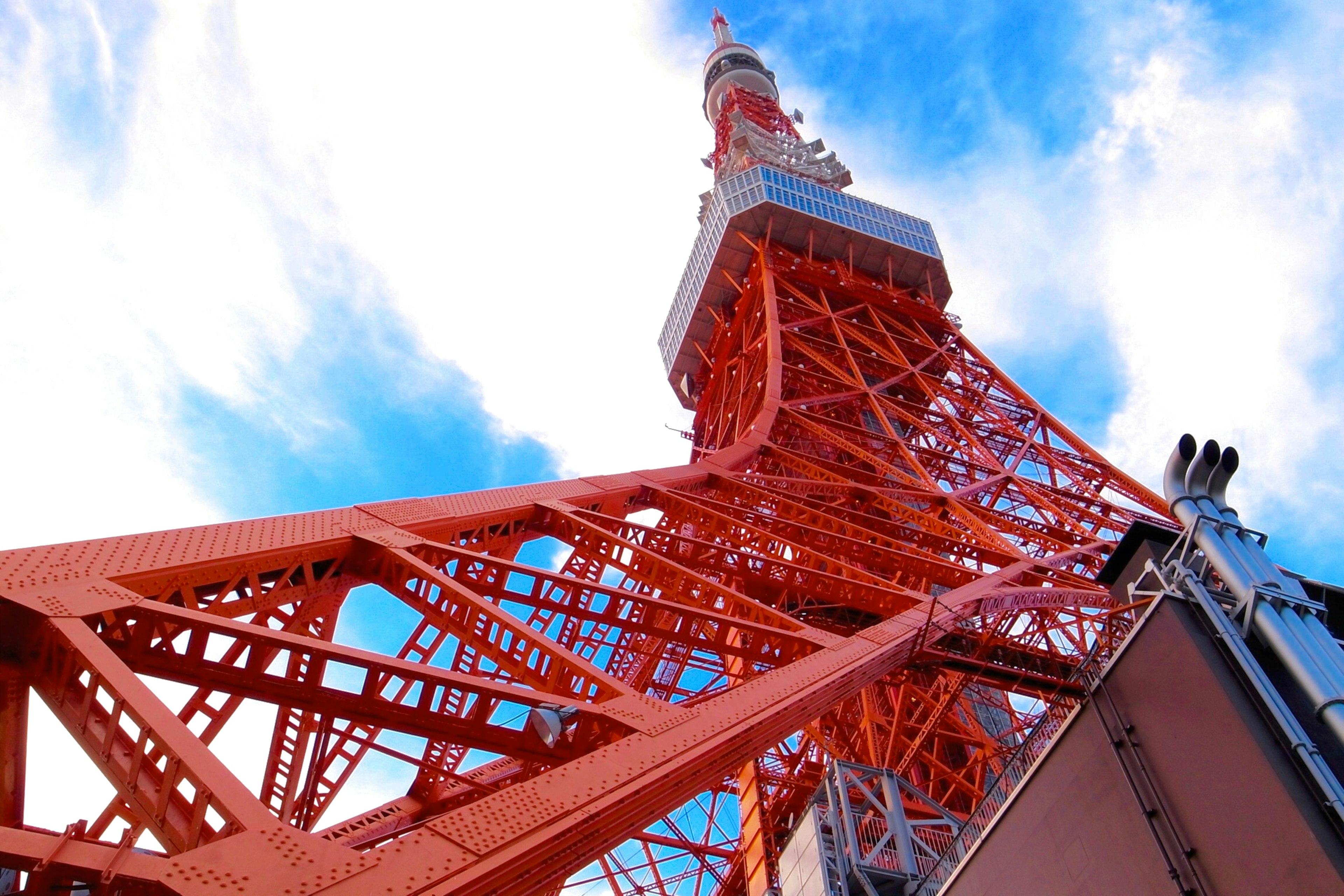 Die orangefarbene Struktur des Tokyo Towers steht im Kontrast zu einem hellblauen Himmel