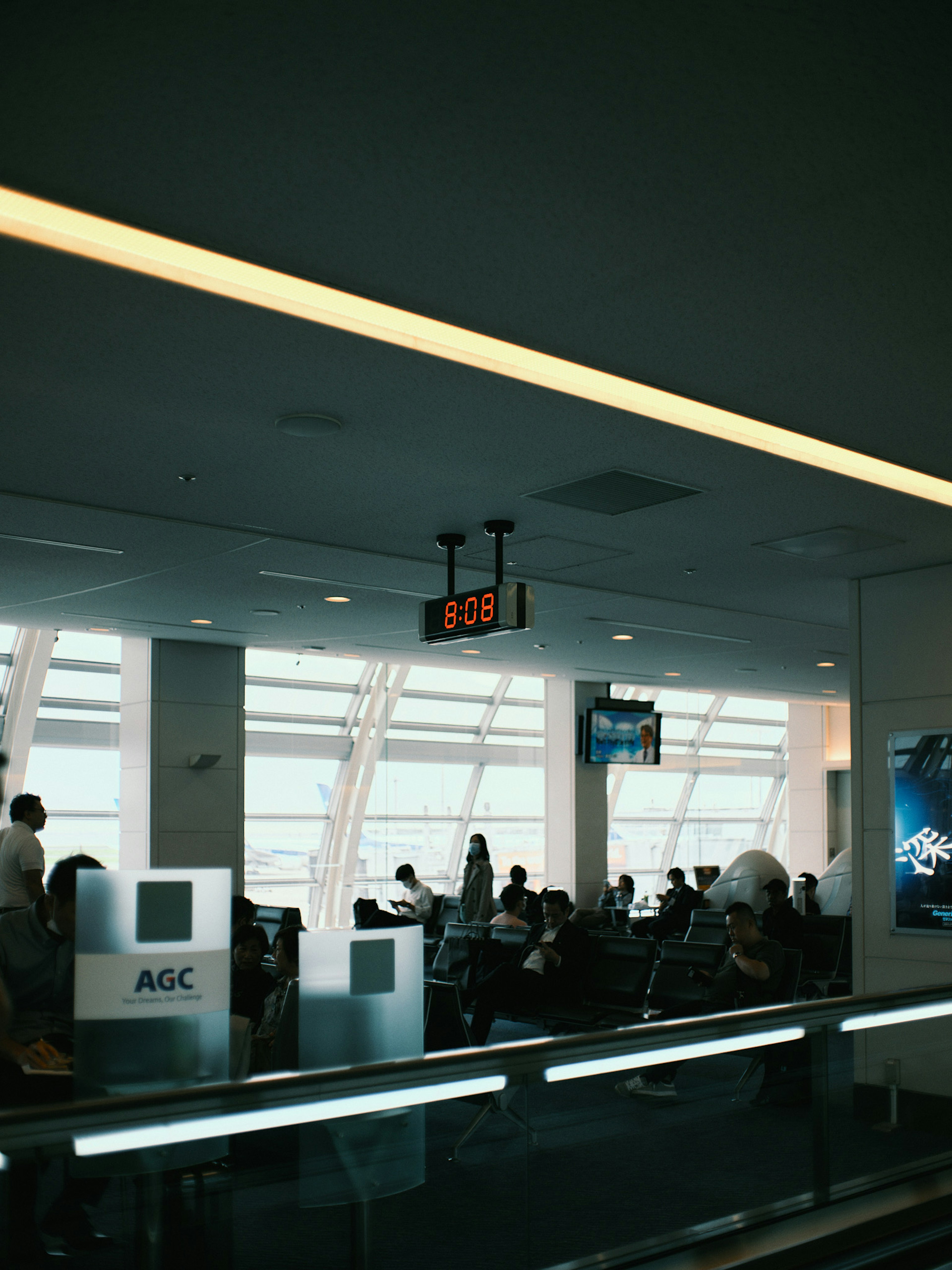 Foto de viajeros en un área de espera del aeropuerto con un reloj visible