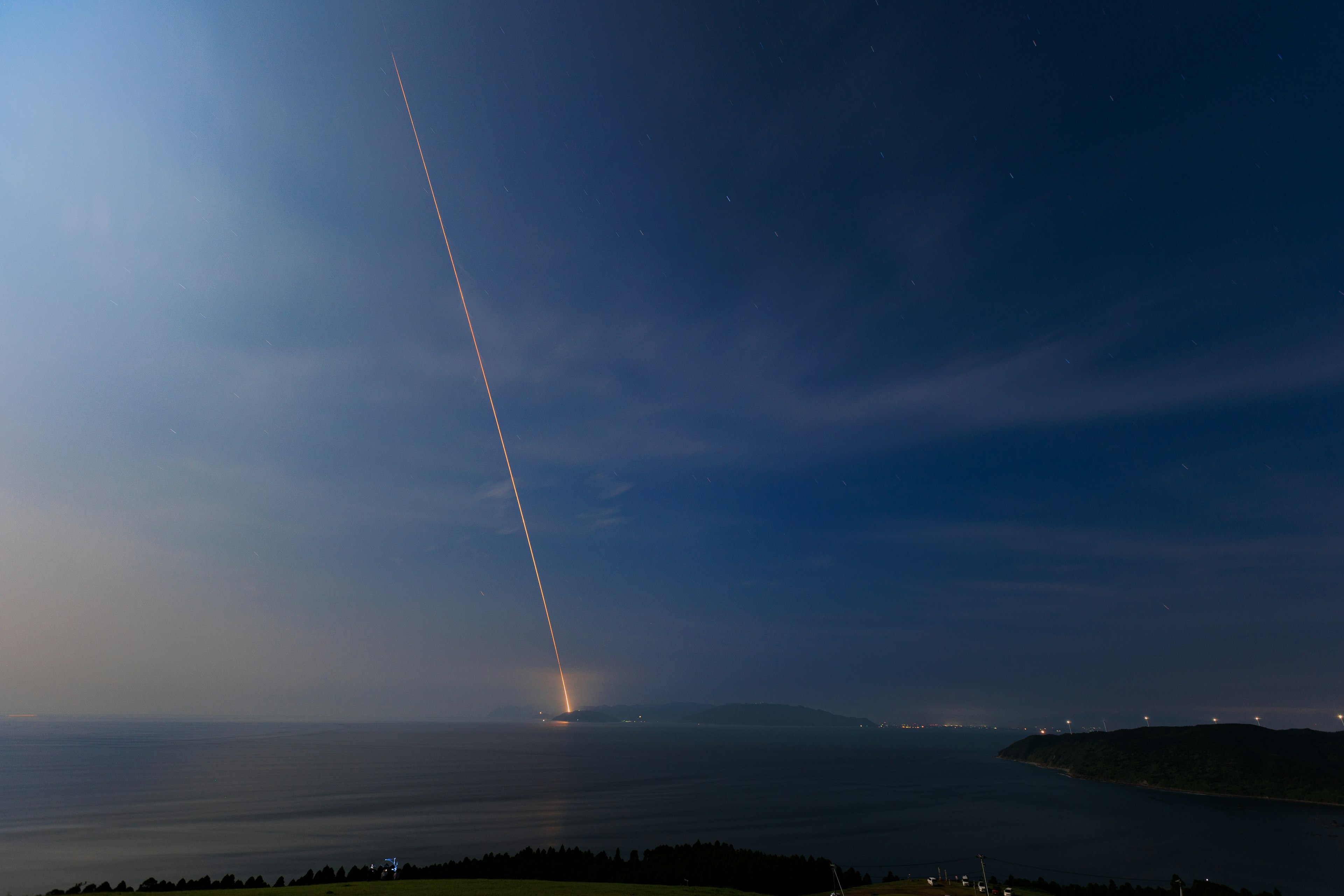 夜空に光線が放たれる海の風景