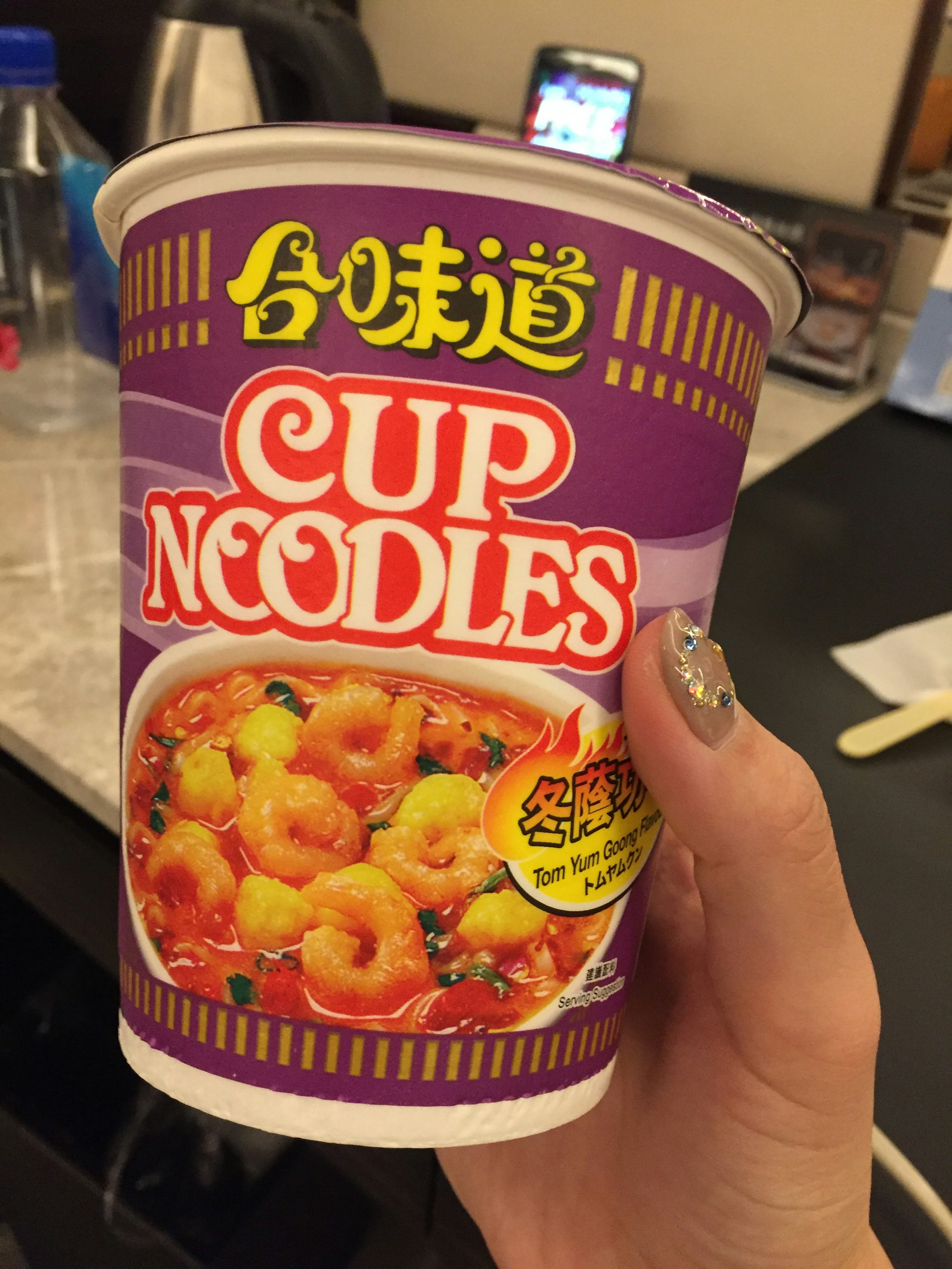 Image d'une main tenant un paquet de Cup Noodles