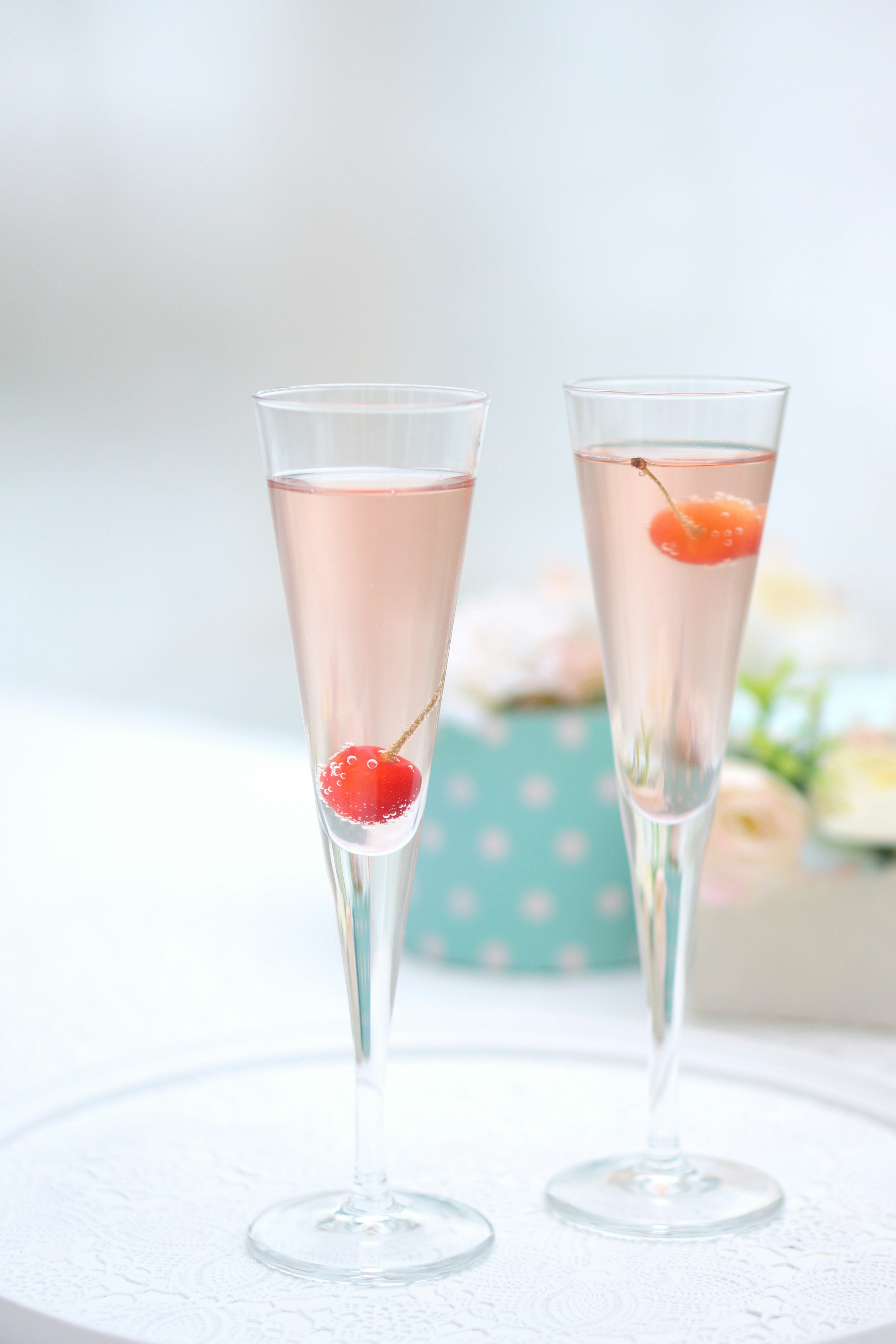 Two champagne glasses with pink drinks and cherries