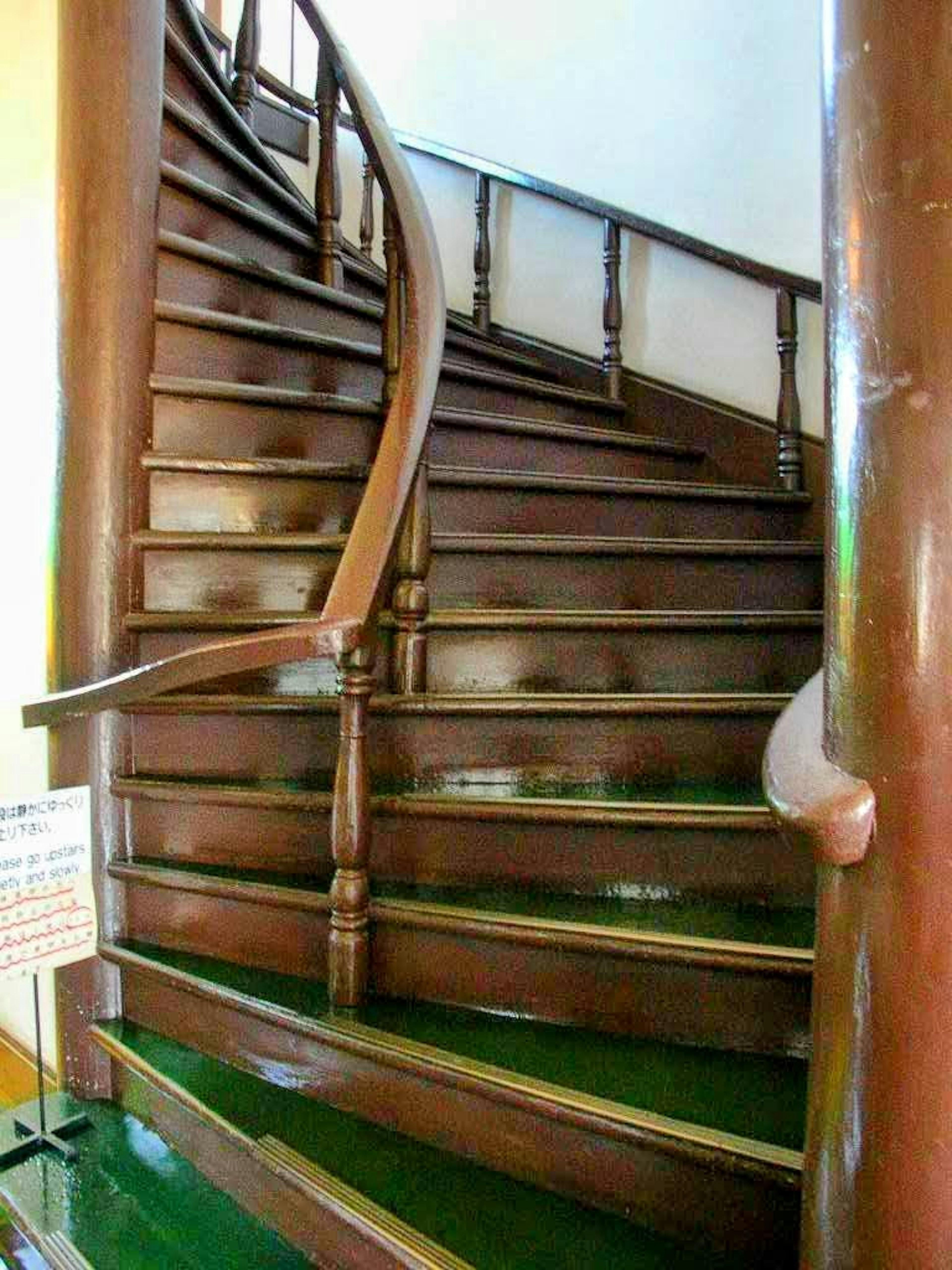 Vue intérieure d'un escalier en bois en spirale avec un sol vert