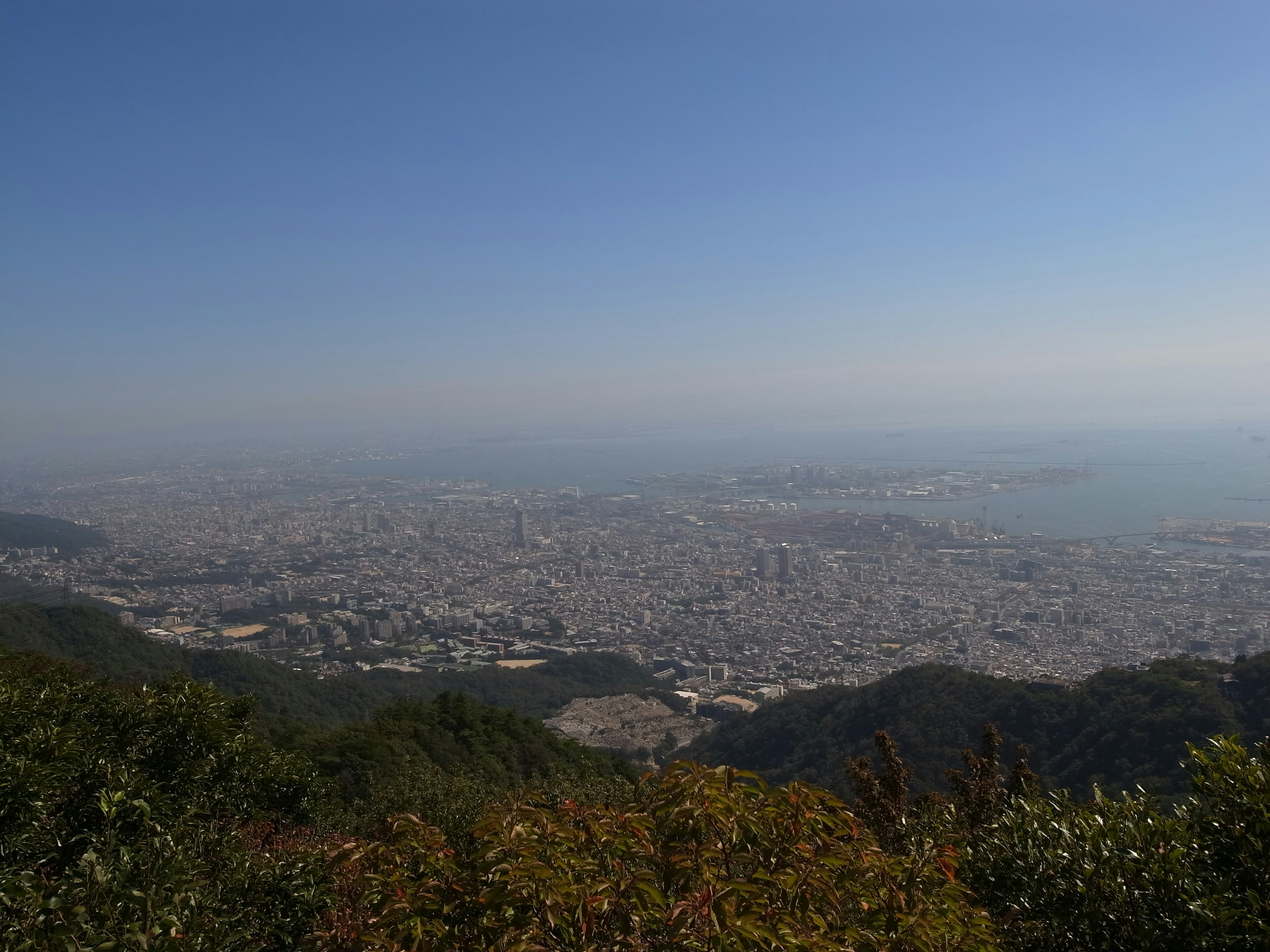 Vue panoramique d'une ville depuis une montagne avec un ciel bleu clair