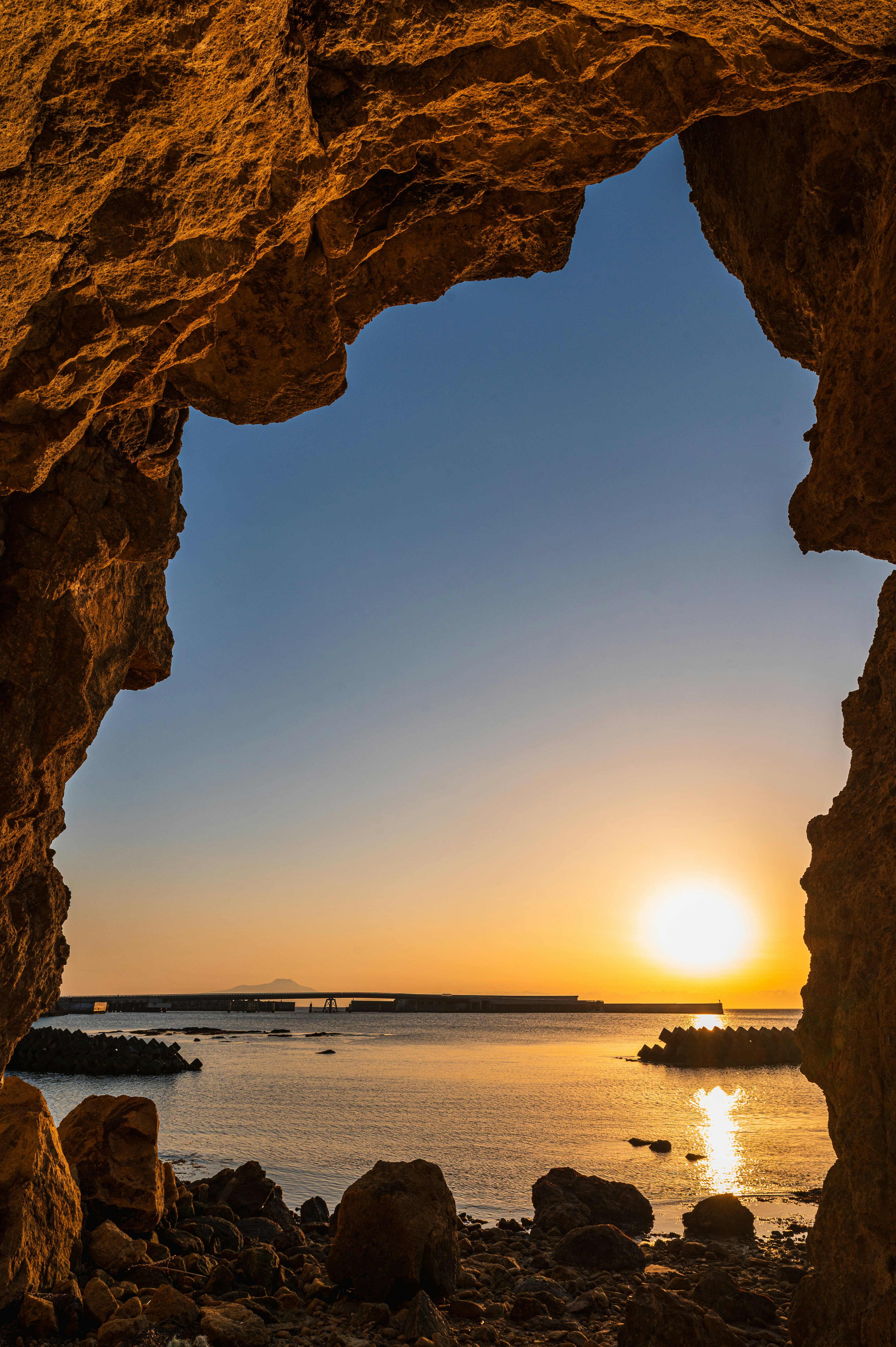 Vue du coucher de soleil et de l'océan à travers une arche rocheuse