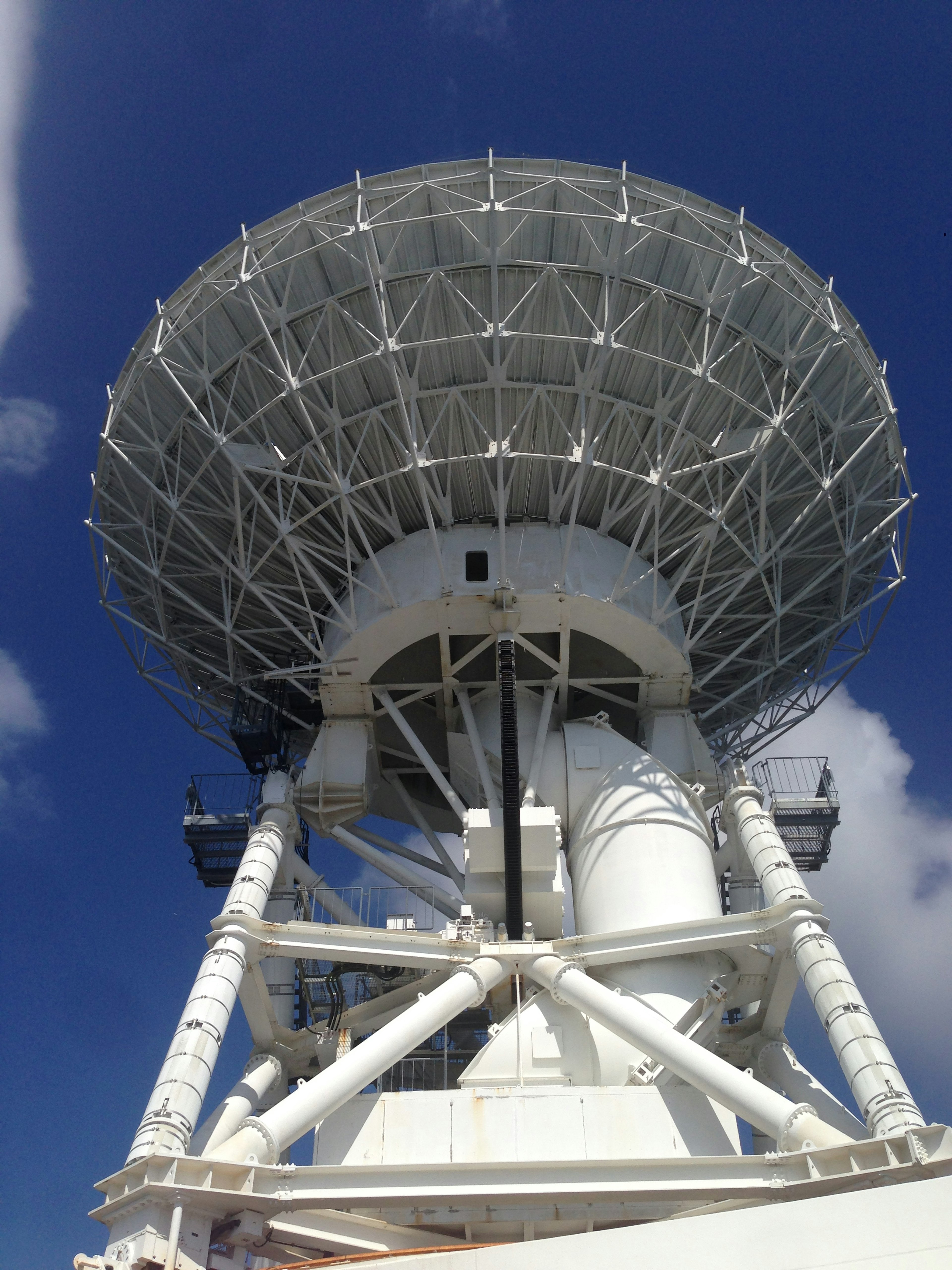 Une grande antenne radar blanche contre un ciel bleu