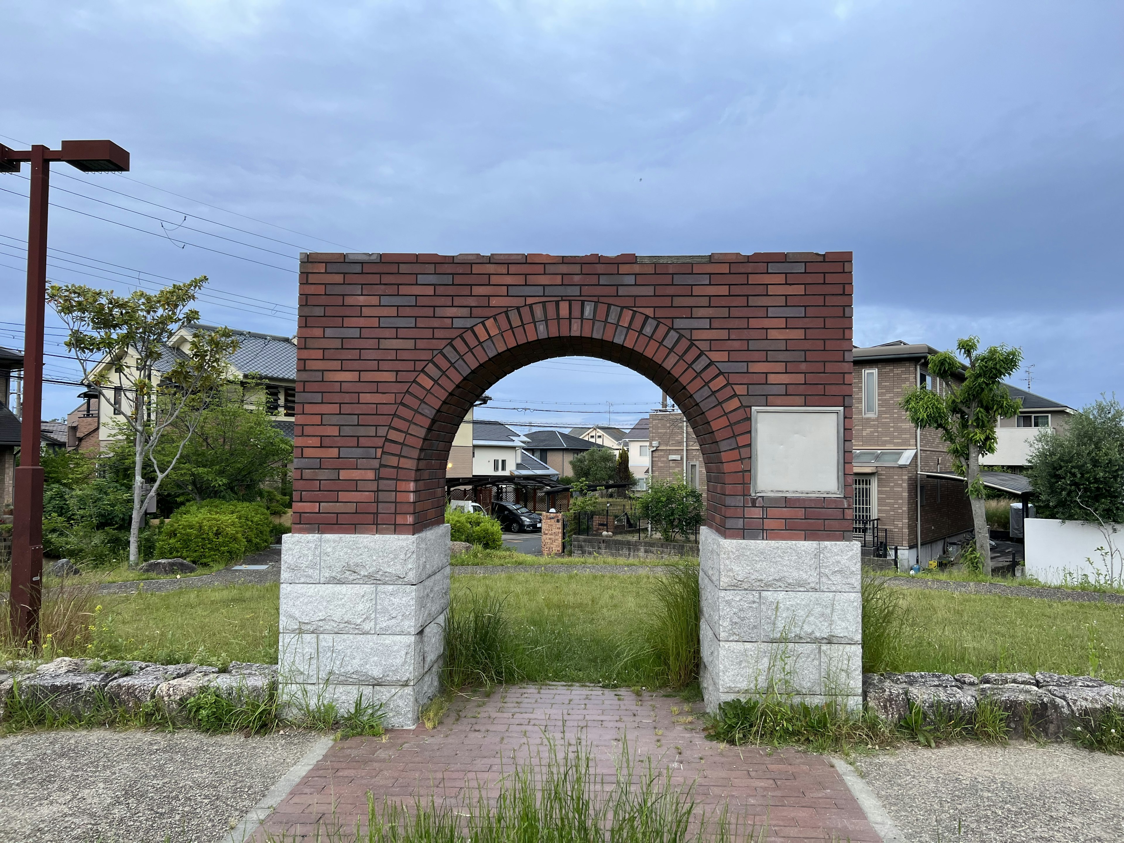 Entrada de arco de ladrillo rodeada de hierba y casas