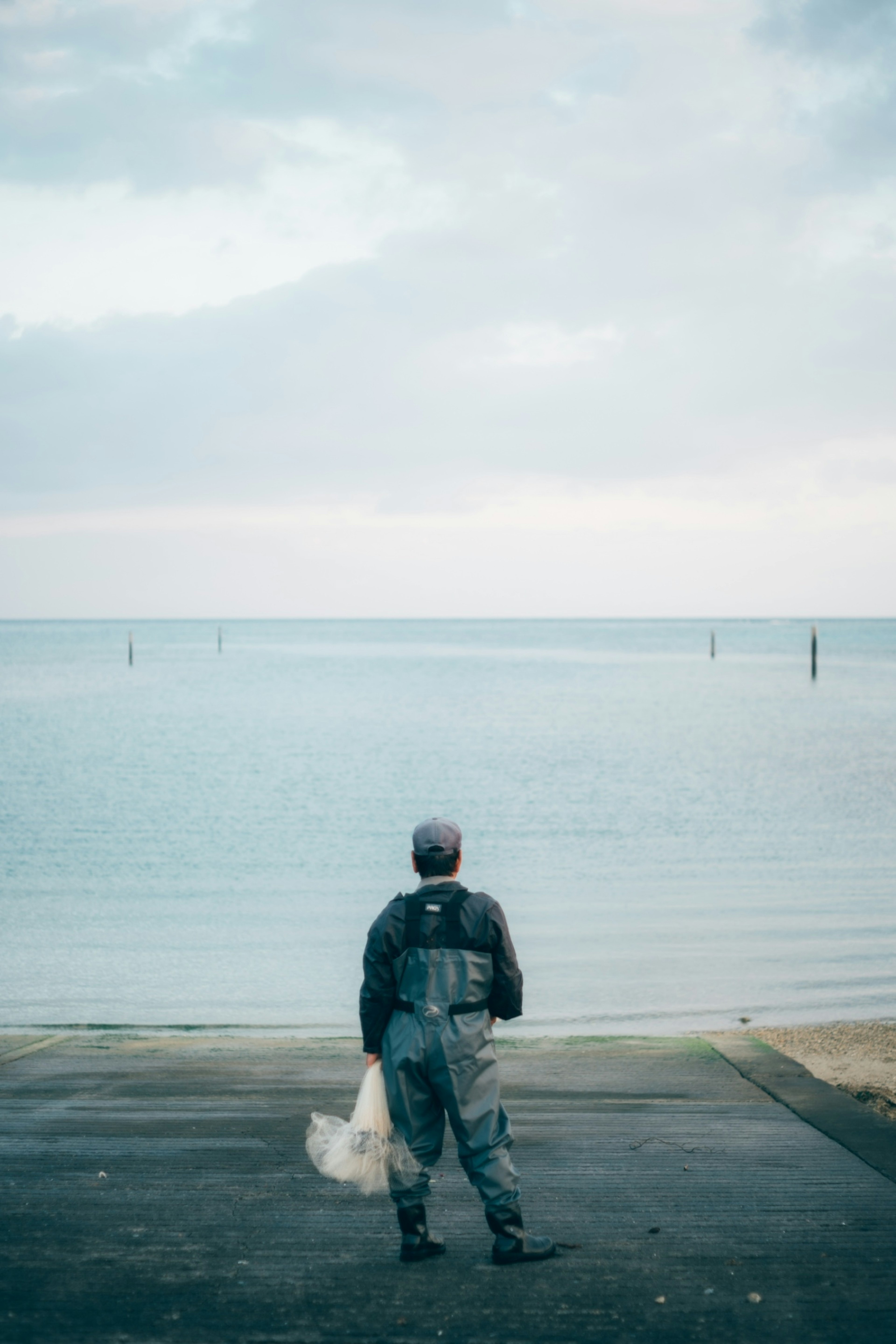 Fischer, der auf das Meer blickt mit einem ruhigen Ozean im Hintergrund