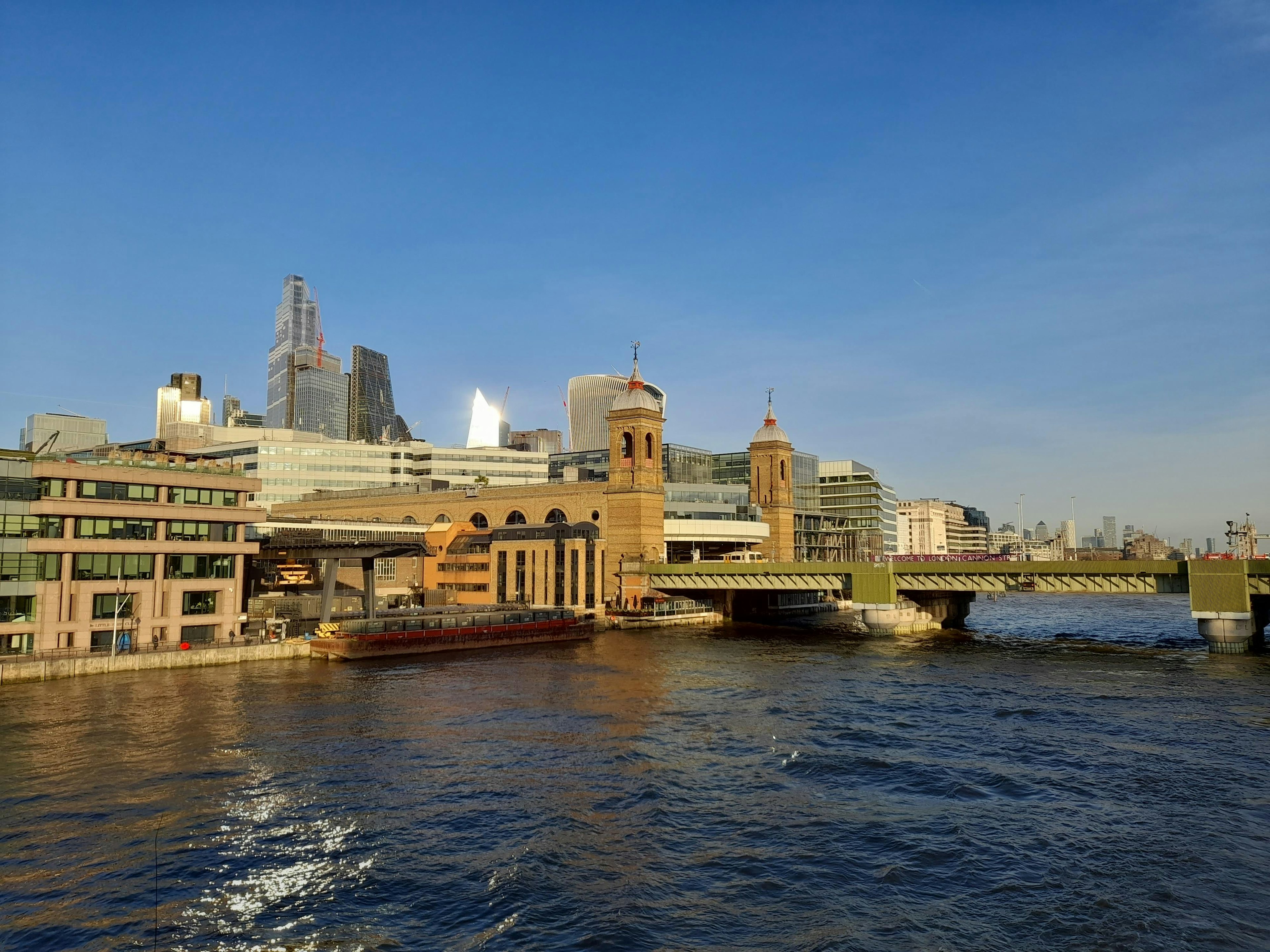 A beautiful riverside view showcasing buildings and a bridge against a clear blue sky