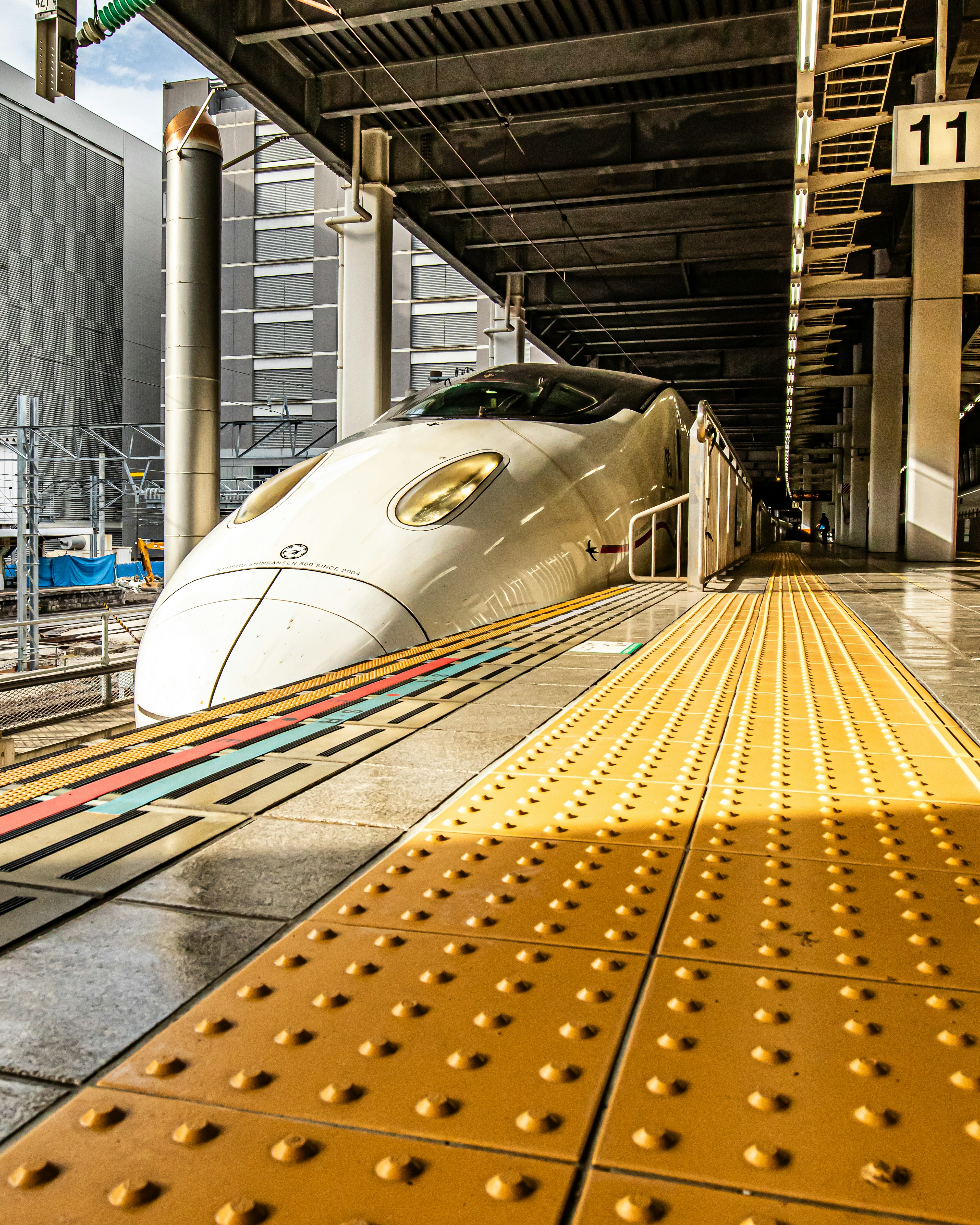 Weißer Shinkansen-Zug wartet am Bahnhof mit gelbem taktilem Belag